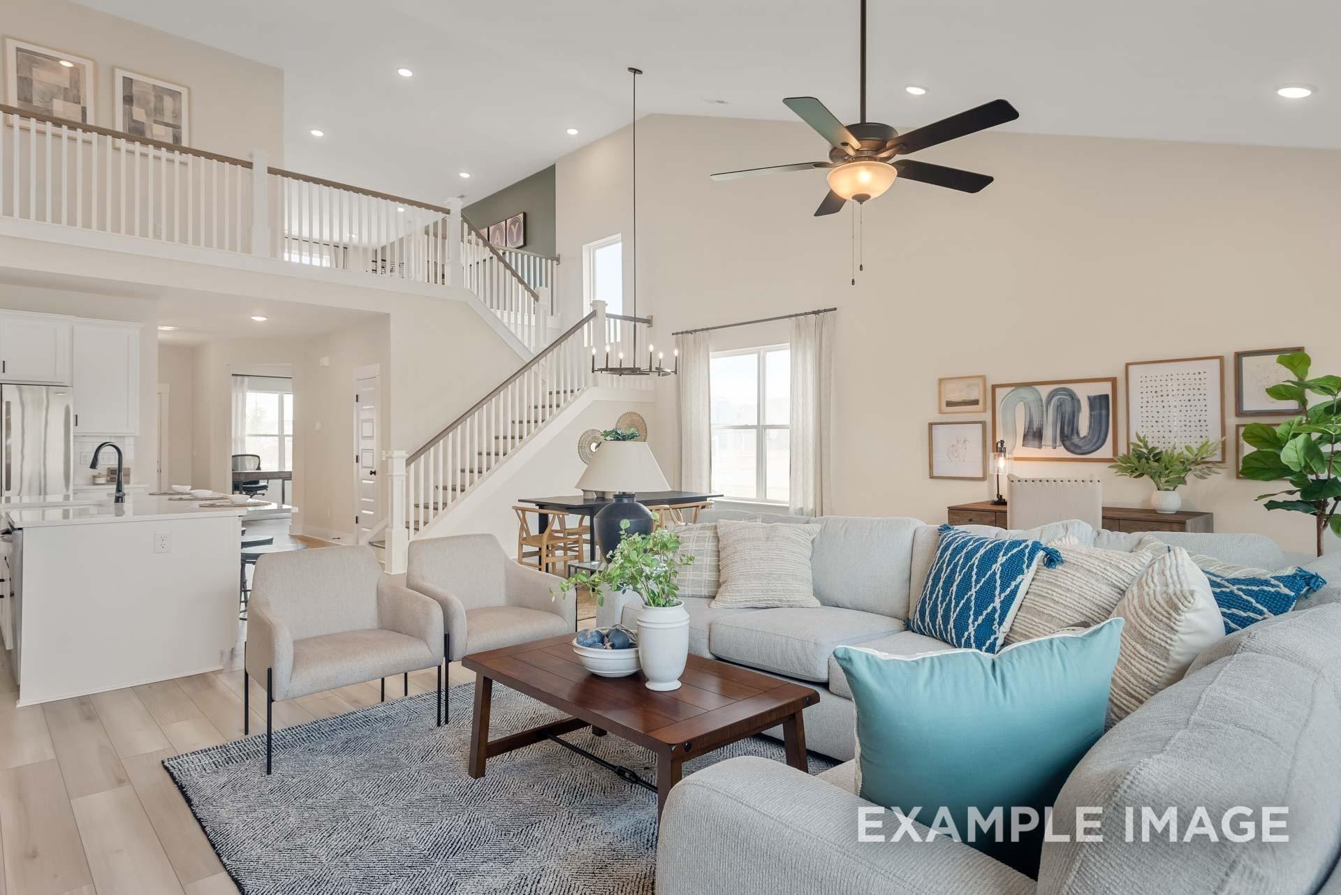 Spacious open living room with gray sectional sofa, wooden coffee table, plants, and staircase to upper level in Davidson Homes Ridgeport C, Gallatin TN