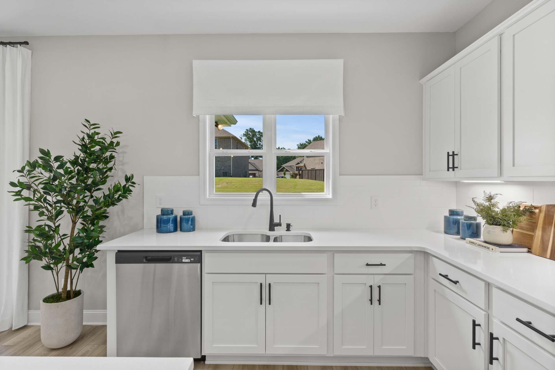 Spacious white kitchen at Creek Grove in New Market Alabama with shaker cabinets, quartz counters, stainless sink and backyard view