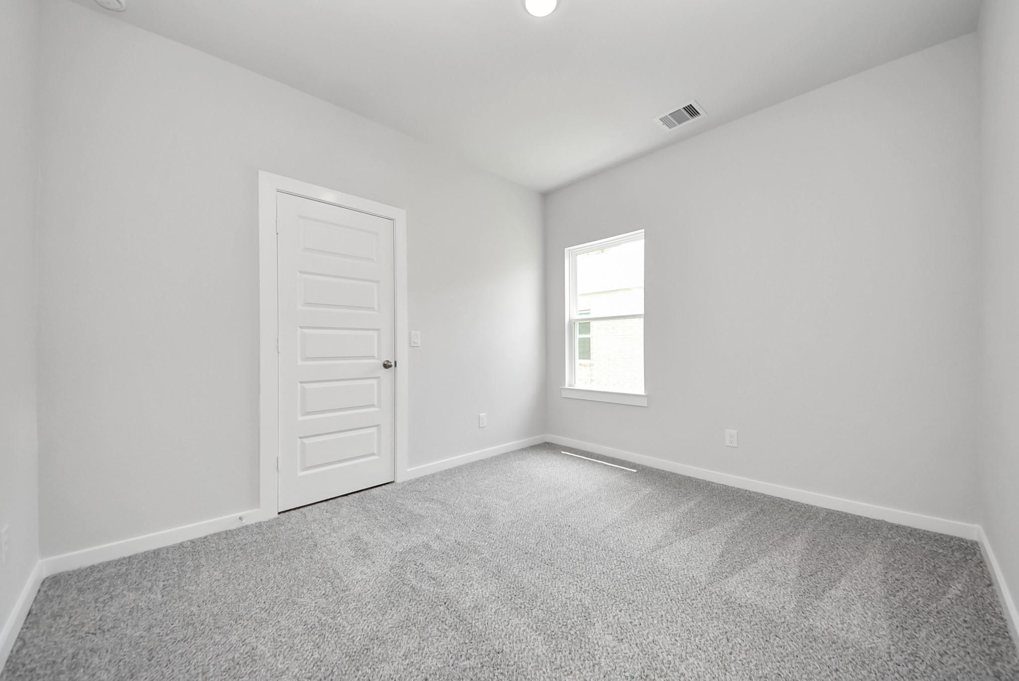 Spacious bedroom with grey carpet and white walls in The Sabine E floor plan by Davidson Homes in Windmill Estates, Magnolia.
