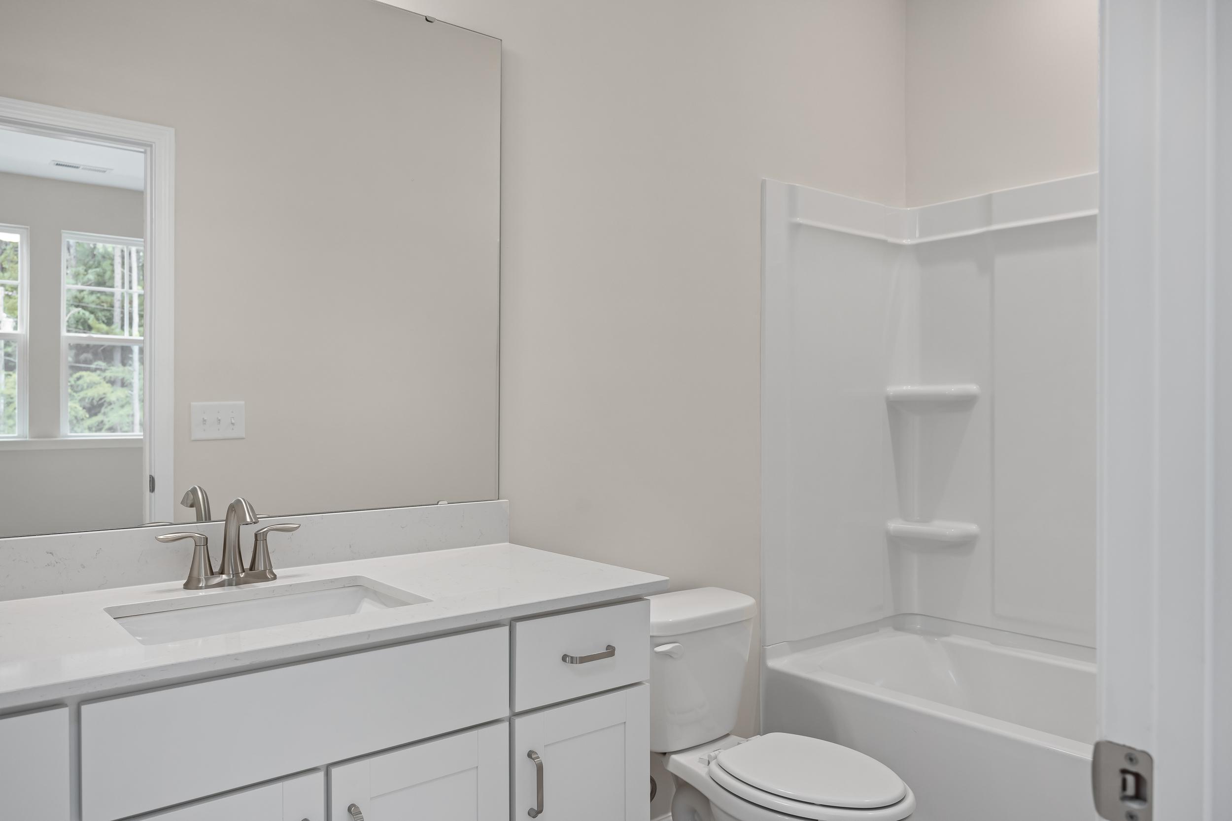 Spacious master bathroom in The Beech A with white vanity, soaking tub, walk-in shower, and neutral walls