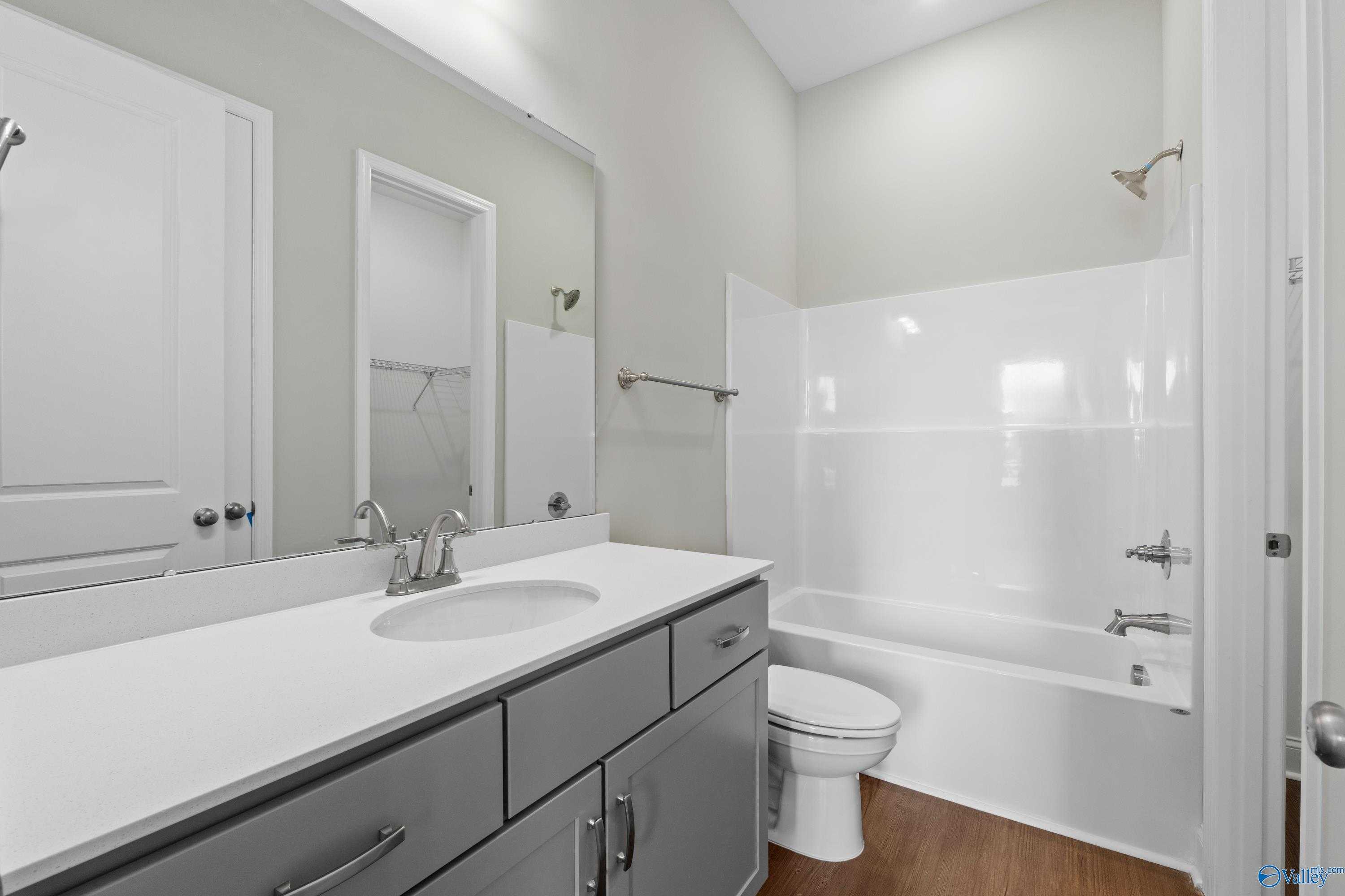 Modern guest bathroom with white tub-shower combo, single vanity, gray cabinets, and neutral walls in Davidson Homes The Arcadia, Huntsville, Alabama