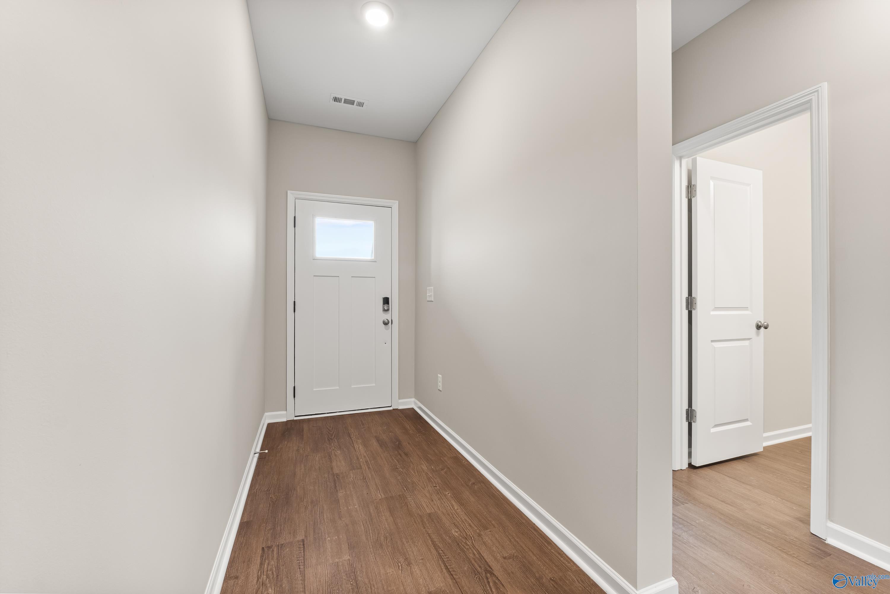 Bright hallway with light gray walls, hardwood floors, and white doors in Davidson Homes The Phoenix, Fayetteville, TN