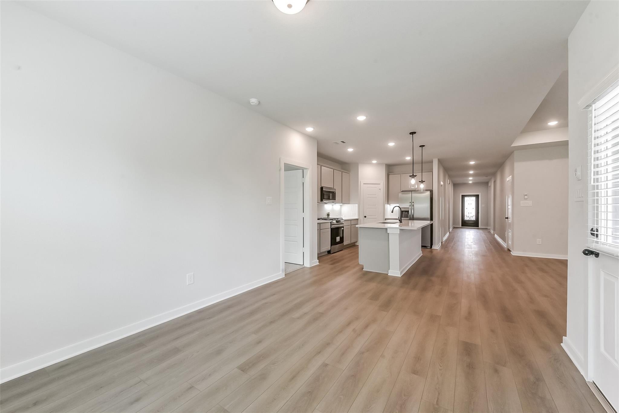 Open kitchen with white shaker cabinets, quartz island, and stainless appliances in The Everett C floor plan, Crosby, Texas