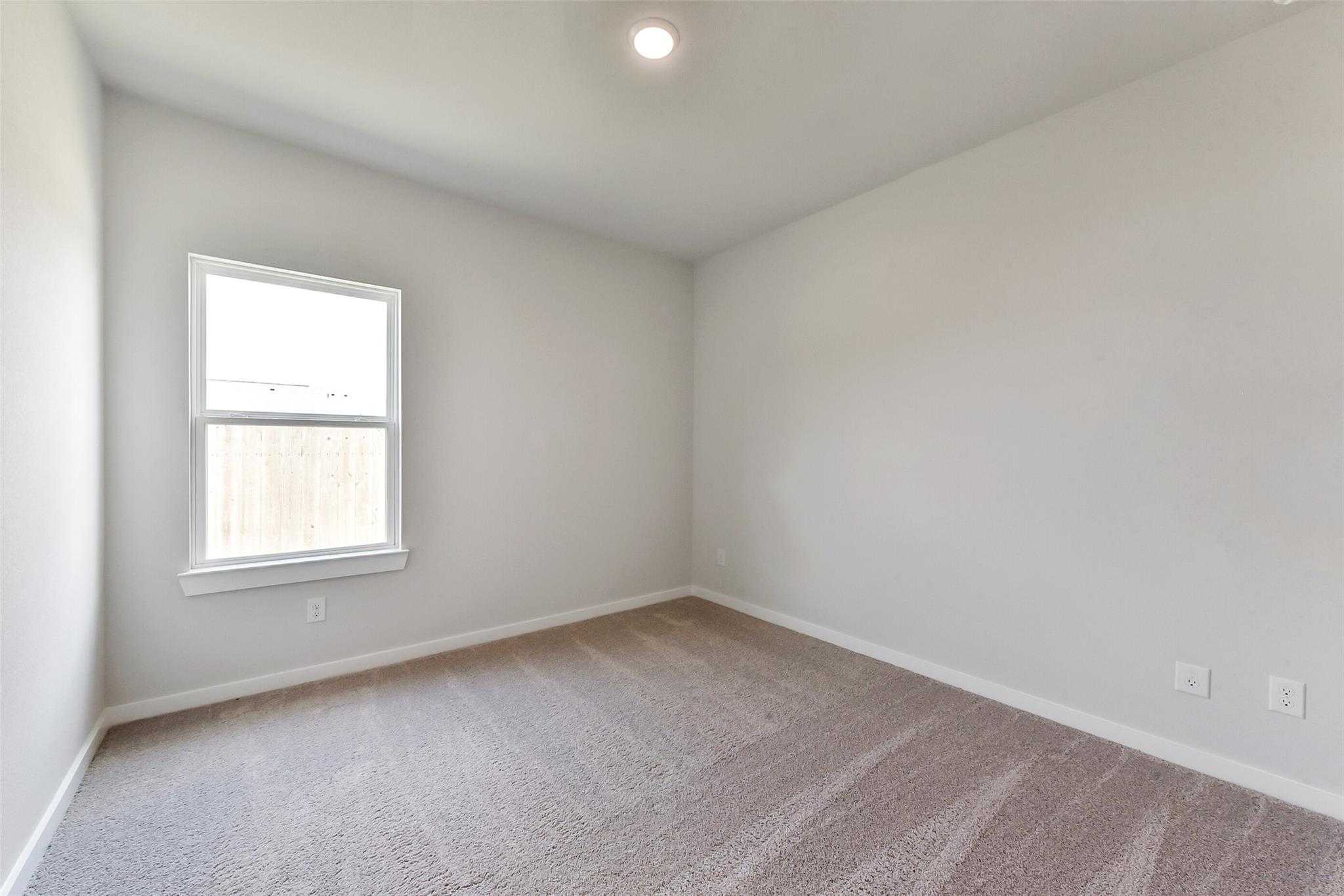 Spacious empty bedroom with beige walls, carpet floor, and window blinds in Davidson Homes The Frio F, Dayton Texas