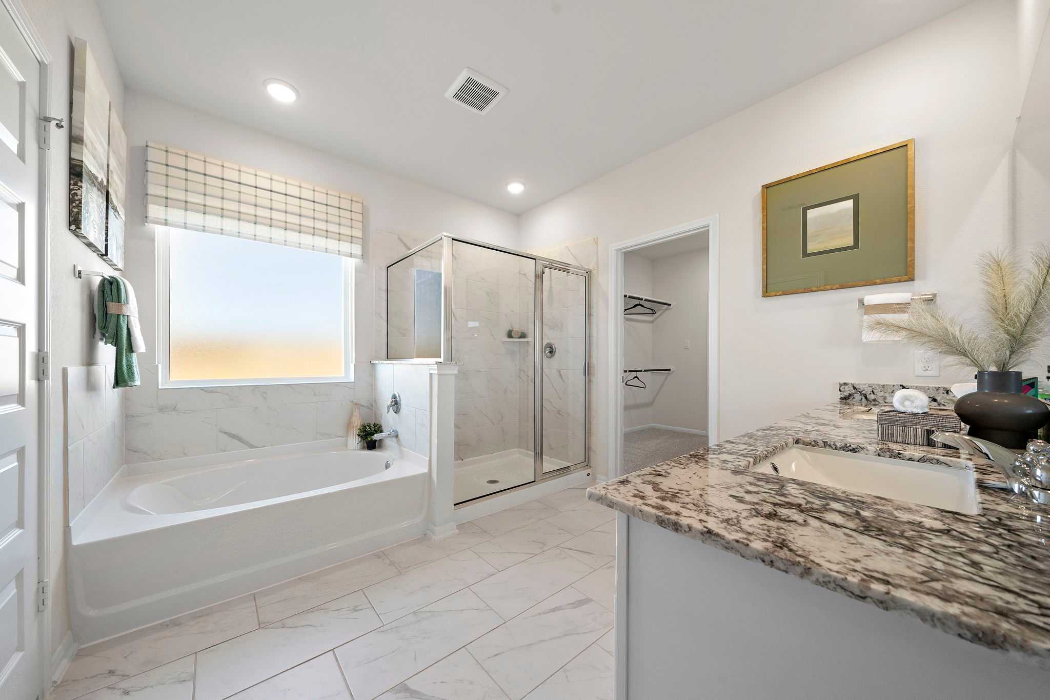 Spacious primary bathroom at River Ranch Meadows in Dayton Texas with freestanding tub walk-in shower granite vanity and natural light