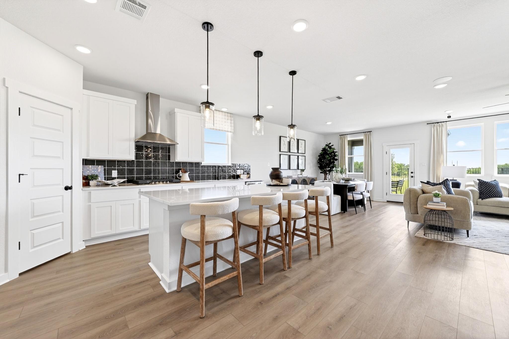 Open-concept kitchen and living area at Parks at Foster Crossing in Anna, TX featuring white cabinetry and a kitchen island.