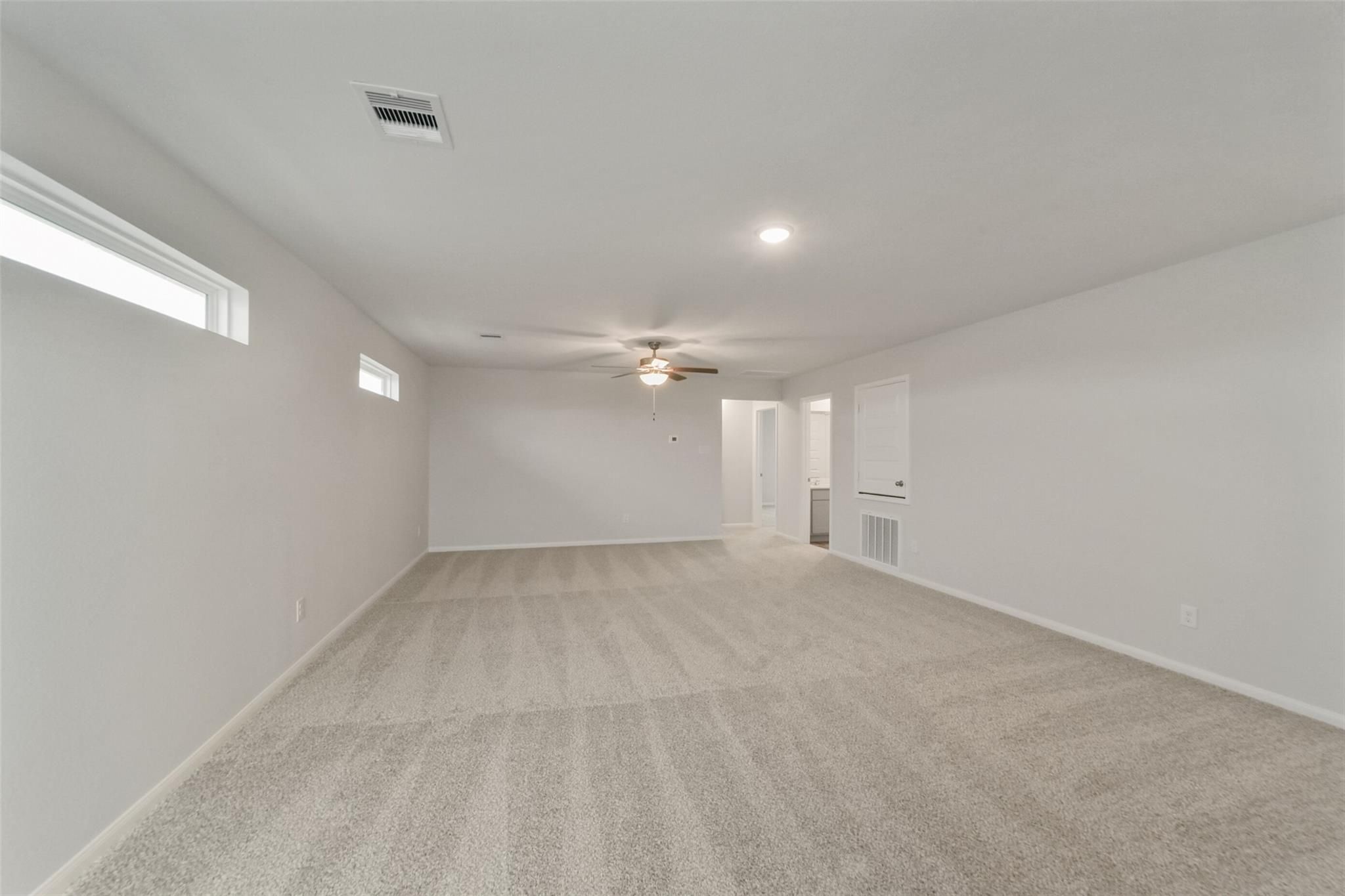 Spacious empty bedroom with beige carpet, ceiling fan, clerestory windows in 5-bed San Marcos E home, Beasley, Texas