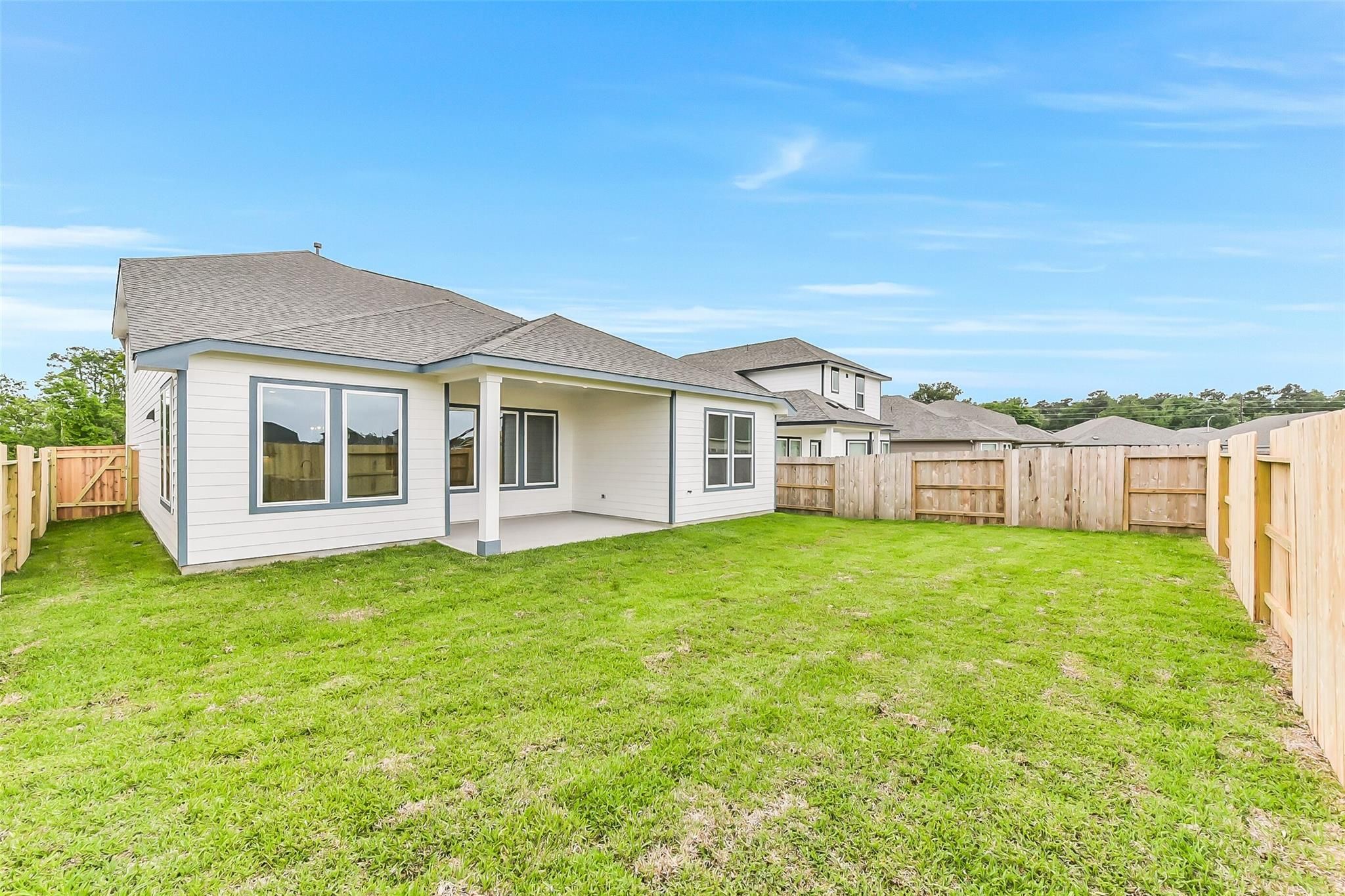 Spacious backyard patio with white-sided two-story home in Davidson Homes Sequoia C, Sundance Cove, Crosby Texas