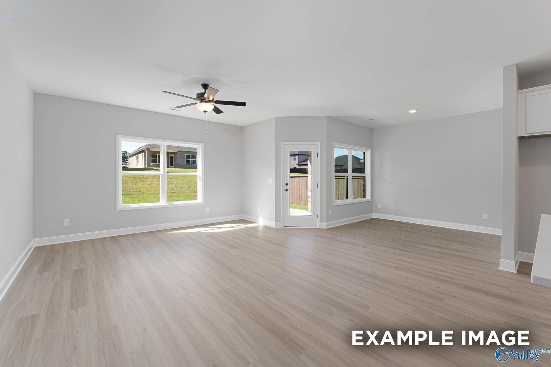 Bright living room with luxury vinyl plank floors, large windows overlooking backyard, ceiling fan in The Daphne D by Davidson Homes, Meridianville