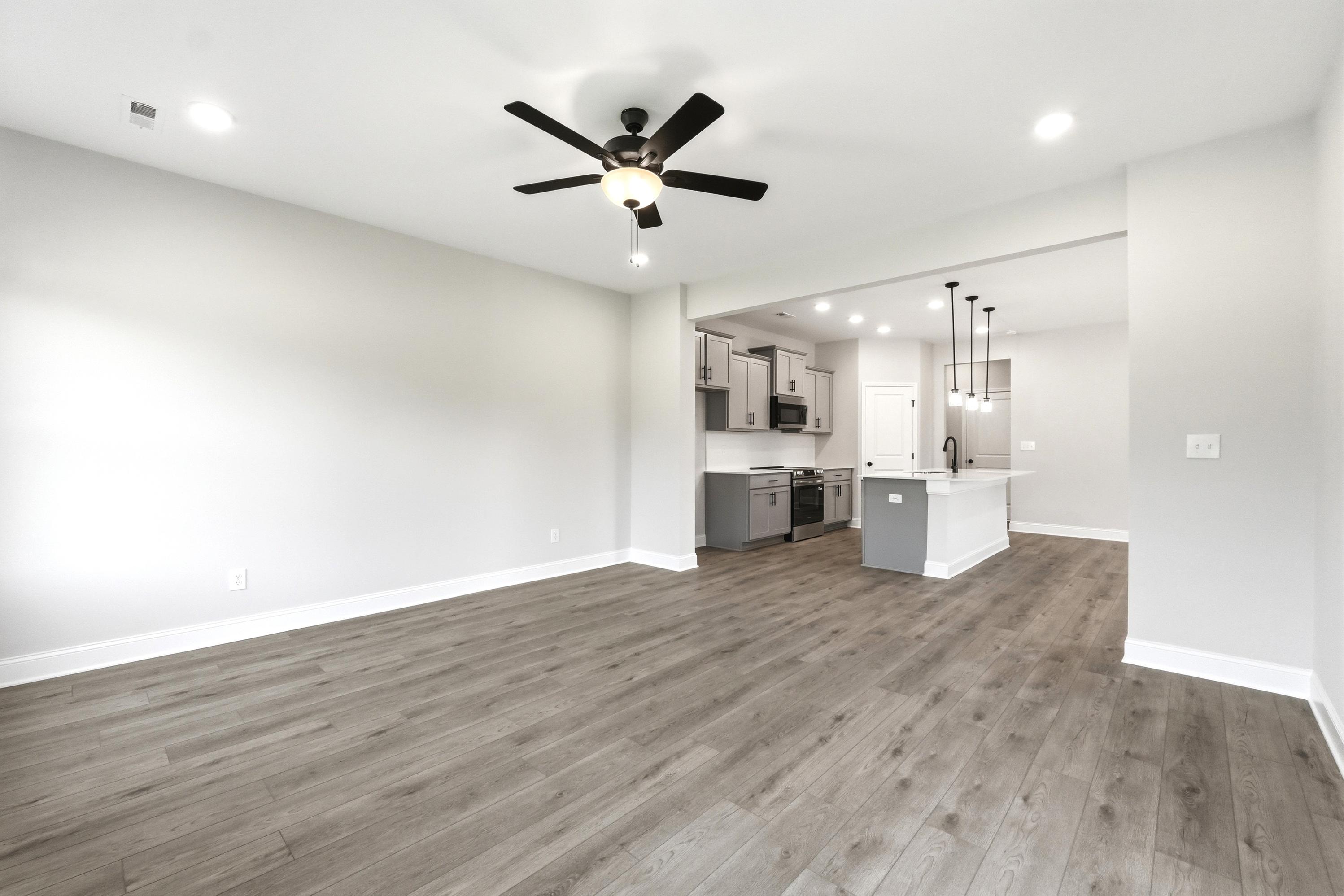 Open-concept living area and kitchen with modern grey cabinets and island in The Russell A floor plan by Davidson Homes.