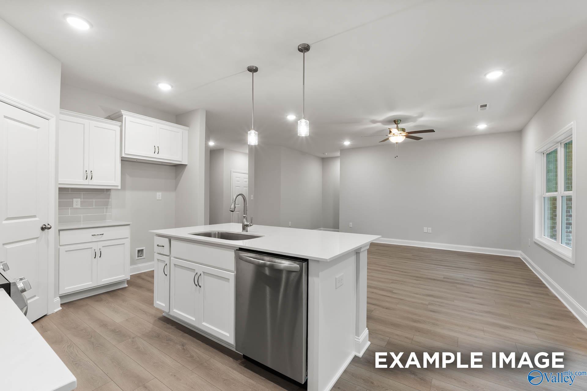 Modern open-concept kitchen with white cabinets, stainless dishwasher, large island sink, and ceiling fan in Davidson Homes The Asheville, Huntsville AL