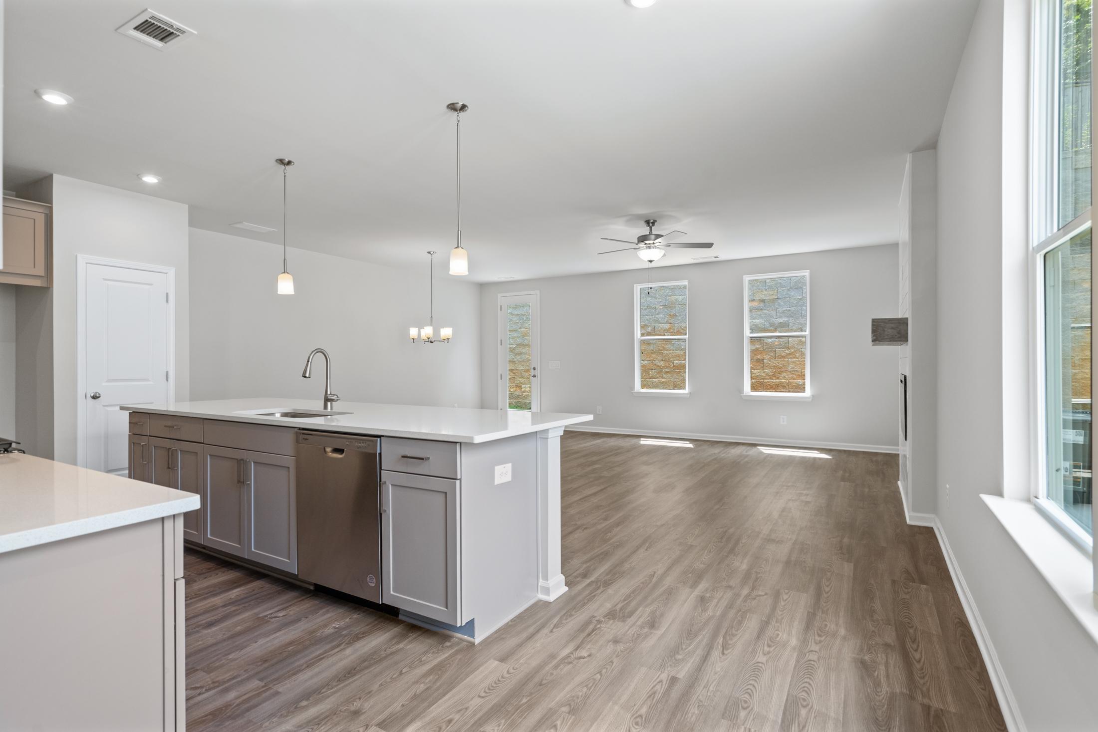 Spacious open-concept kitchen in The Cary A with white quartz island, gray cabinets, hardwood floors, and large windows
