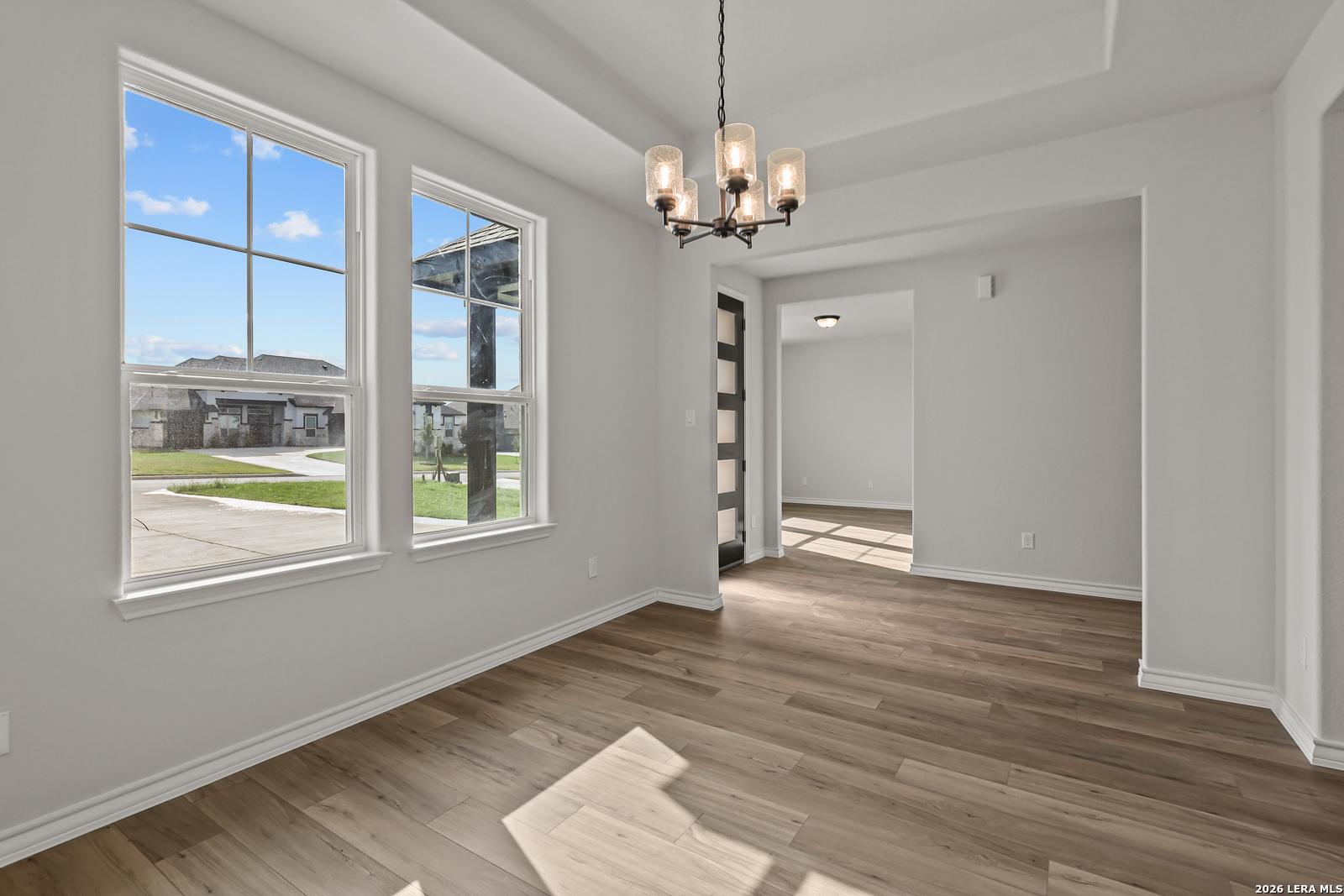 Bright dining area with tray ceiling, chandelier, and large windows in Davidson Homes The Oxford F, Potranco Oaks, Castroville, TX