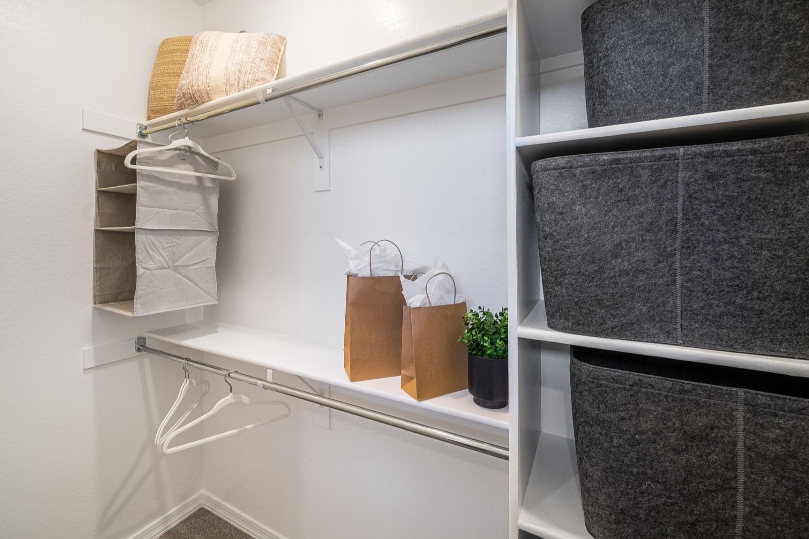 Spacious walk-in closet in The Savannah B master suite featuring shelves, hanging rods, gray baskets, and organized storage