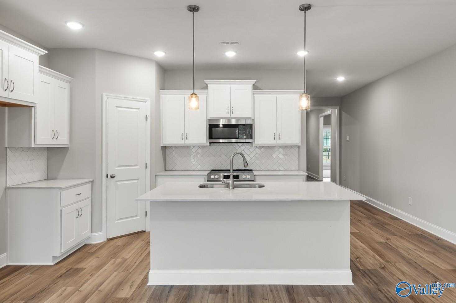 Modern white kitchen with large island, stainless appliances, subway tile backsplash in The Daphne D by Davidson Homes, Athens, AL