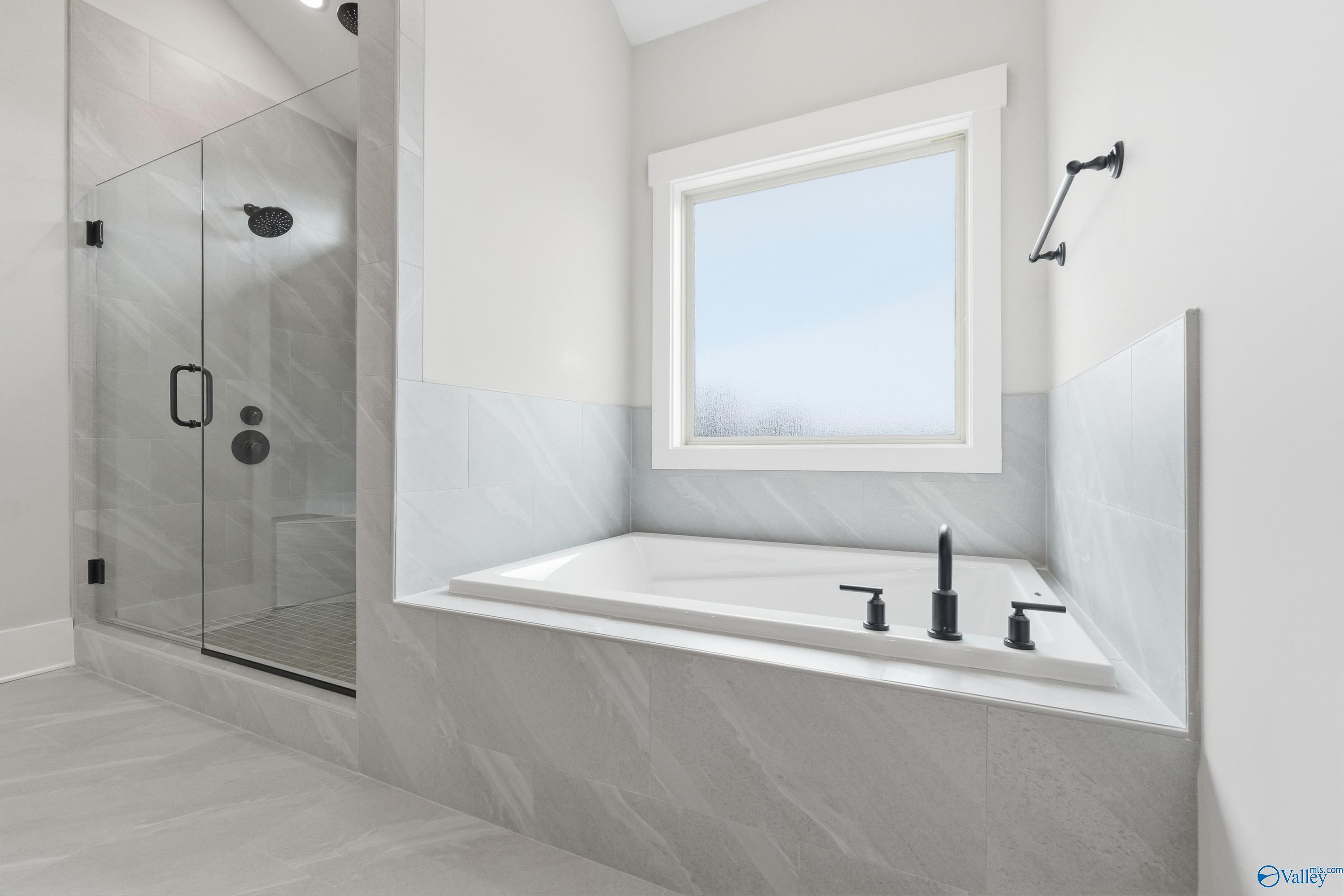 Luxurious master bathroom featuring frameless glass shower, freestanding soaking tub, and large window in Davidson Homes The Finleigh, Meridianville, Alabama