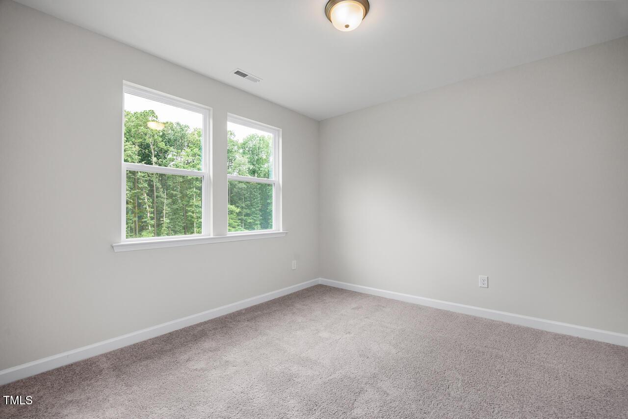 Bright secondary bedroom with large windows and tree views on beige carpet in Davidson Homes The Aspen B, Wake Forest, NC