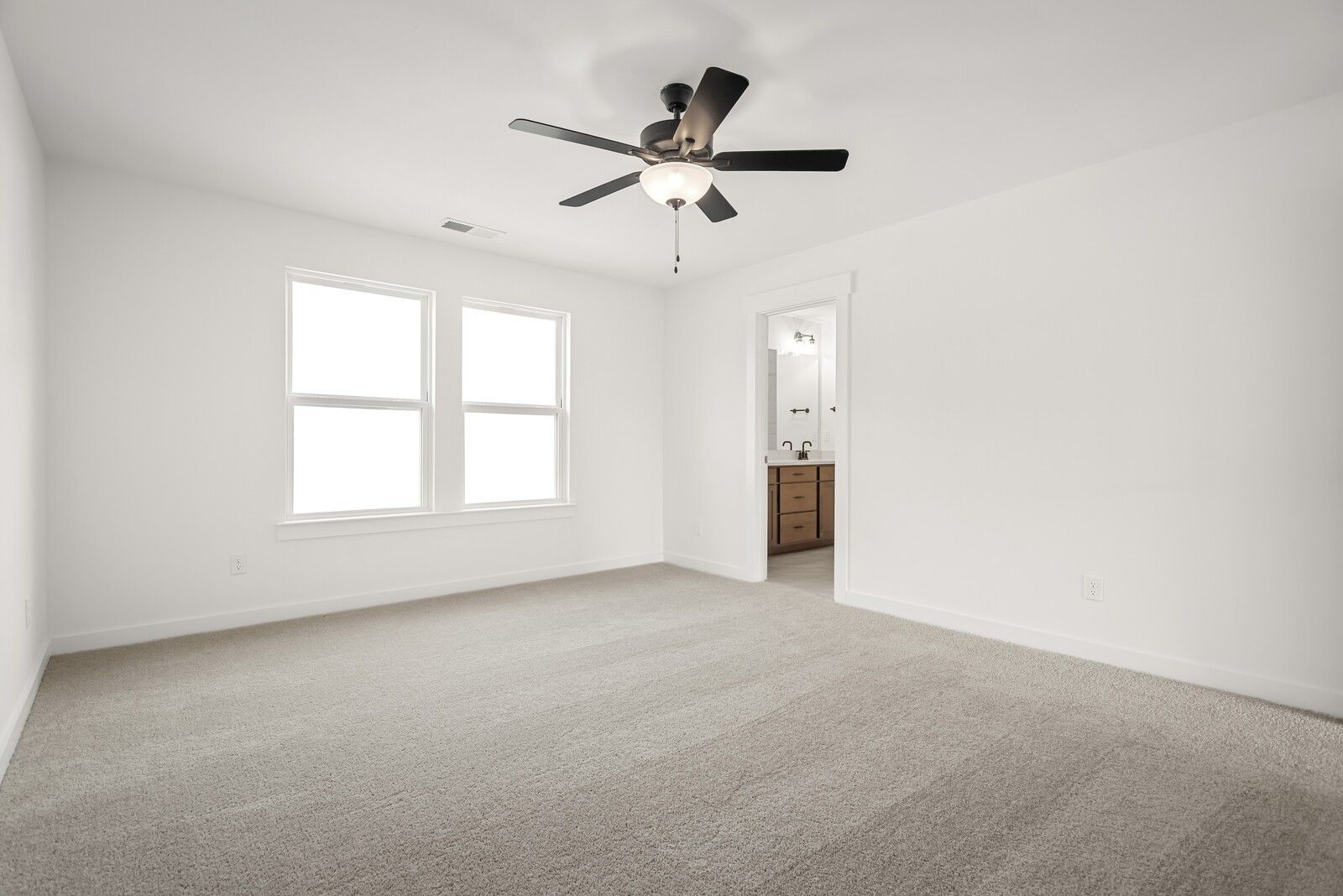 Spacious bedroom with ceiling fan, large windows, and adjacent bath in Davidson Homes The Logan C, Gallatin, TN