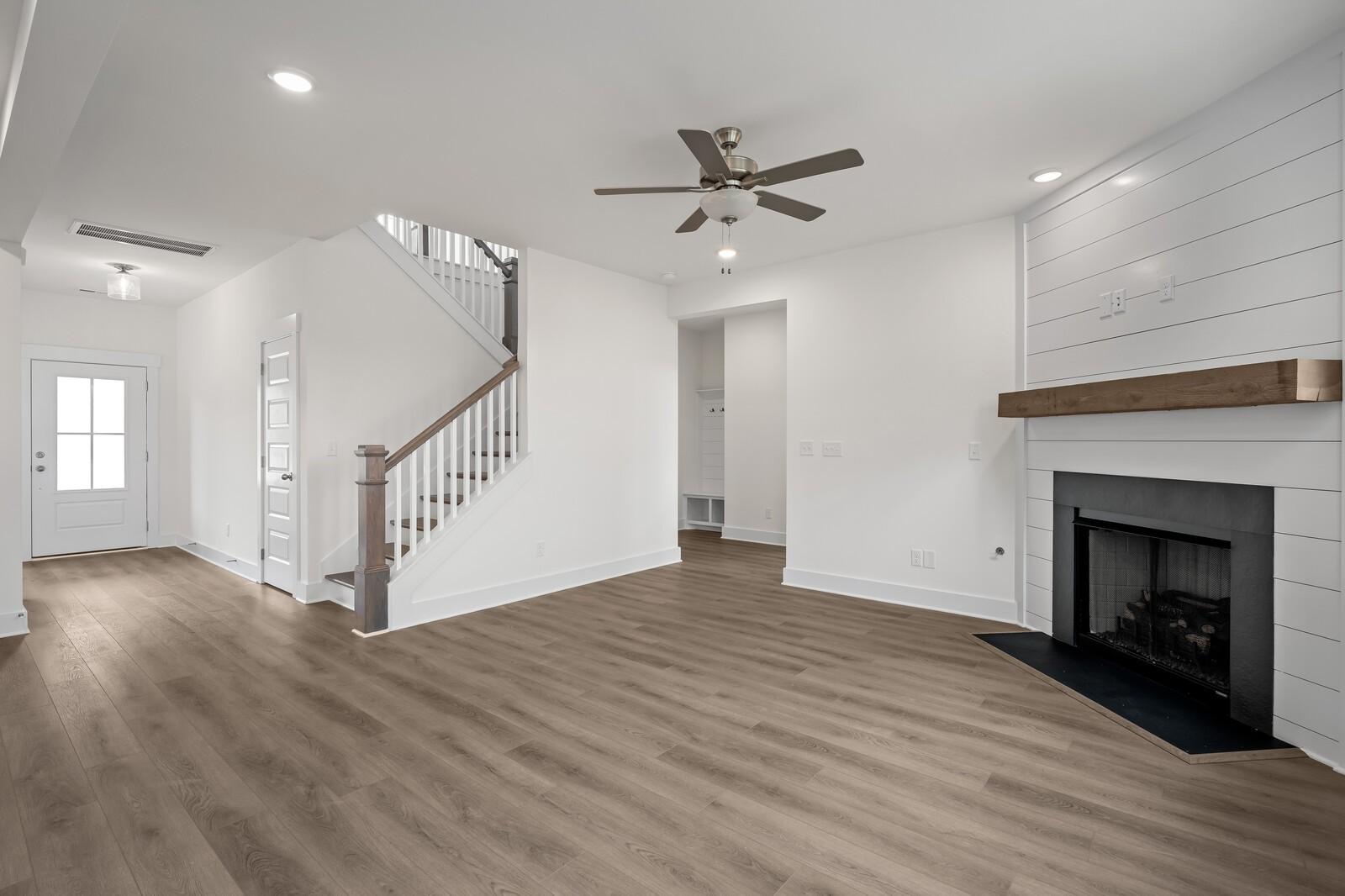 Spacious two-story foyer with grand wooden staircase, shiplap walls, and stone fireplace in The Willow C by Davidson Homes, Gallatin, TN