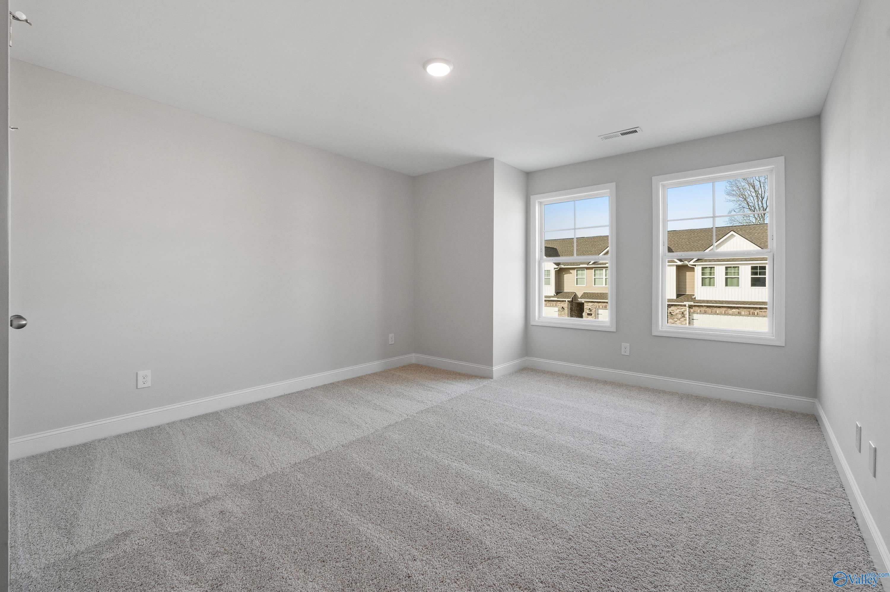 Bright secondary bedroom with light gray walls, carpeted floor, and large windows in Davidson Homes The Camden, Pavilion, Huntsville