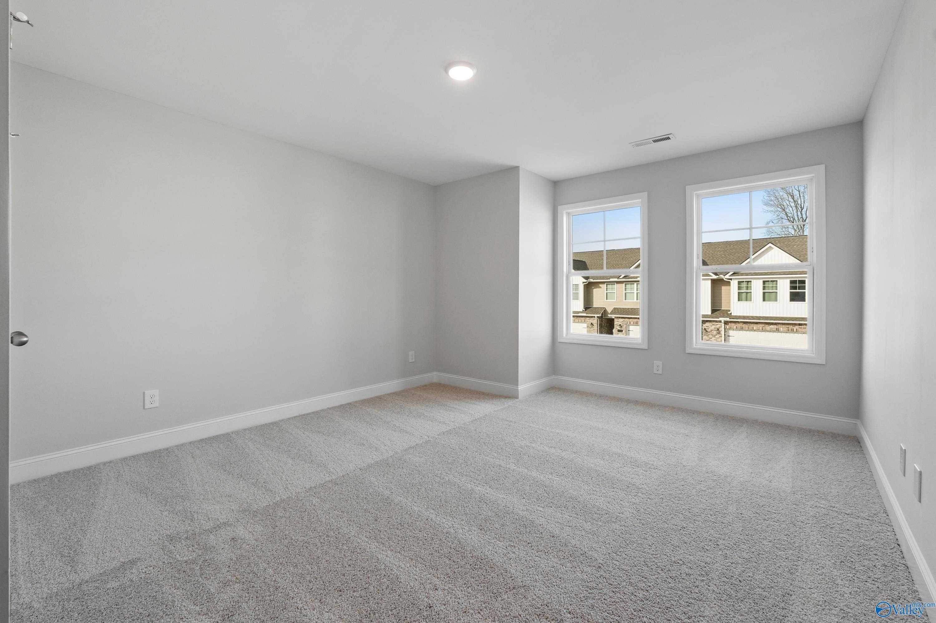 Bright secondary bedroom with light gray walls, carpeted floor, and large windows in Davidson Homes The Camden, Pavilion, Huntsville