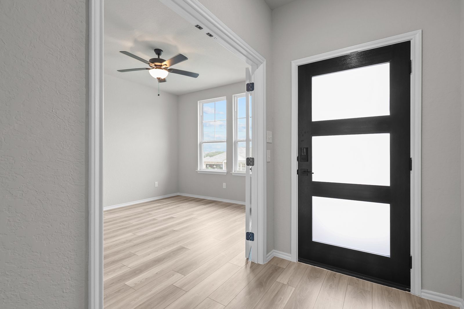 Modern foyer entry with sleek black door and French doors leading to a bright flex room in The Glenwood by Davidson Homes.