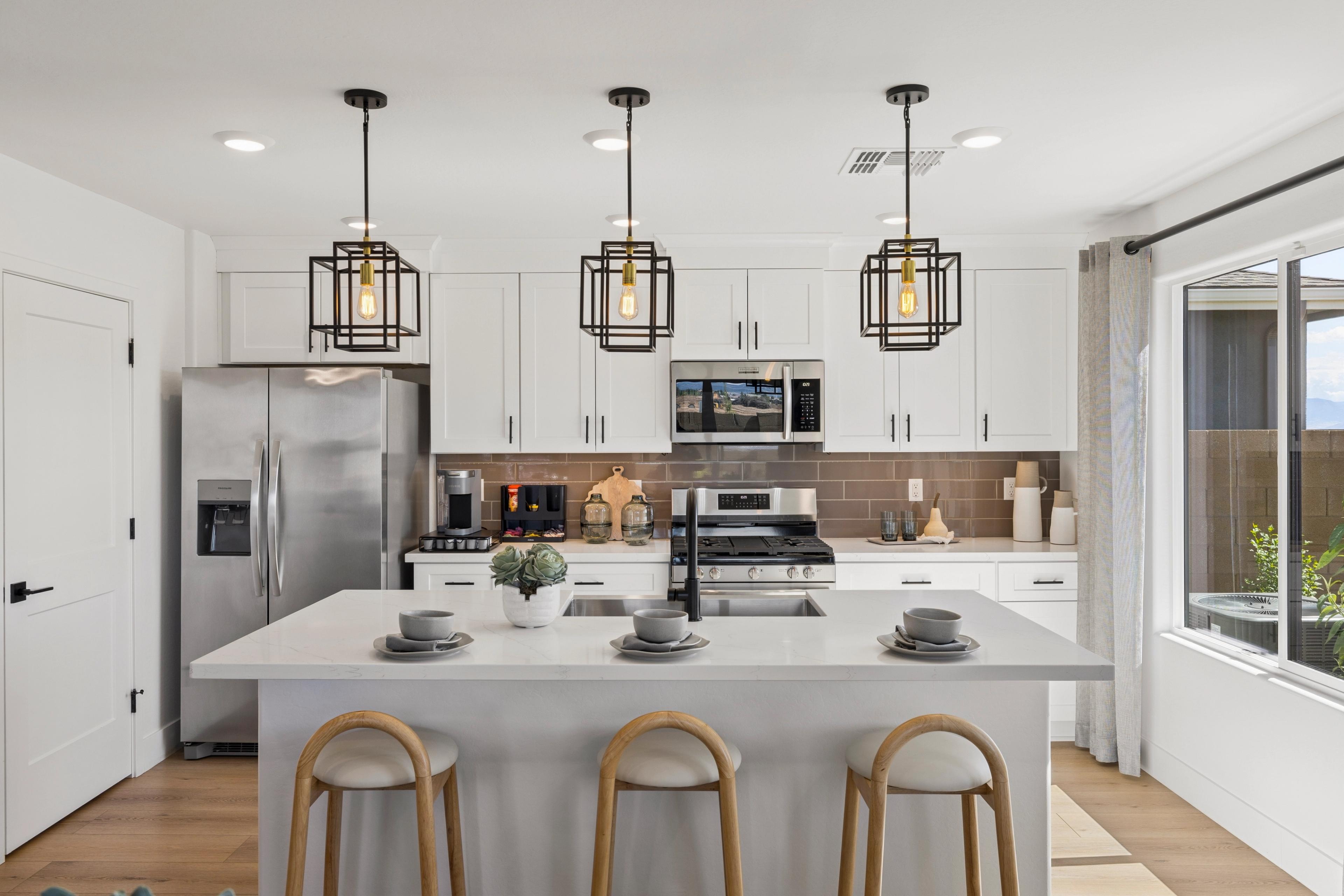 Spacious modern kitchen at South Ranch Southern Collection in Prescott AZ with white quartz island, stainless appliances, and pendant lights