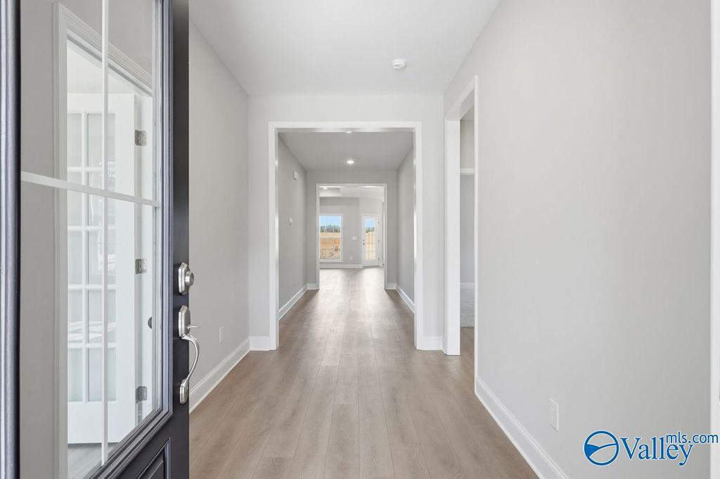 Welcoming entry hallway with light oak floors, white walls, and sidelight door in Davidson Homes The Harrison, Hartselle, AL