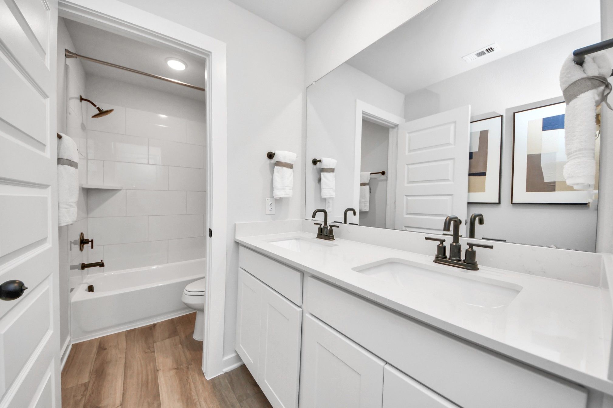Modern bathroom with double vanity, quartz countertops, and tub-shower combo at Robins Landing in Houston by Davidson Homes.