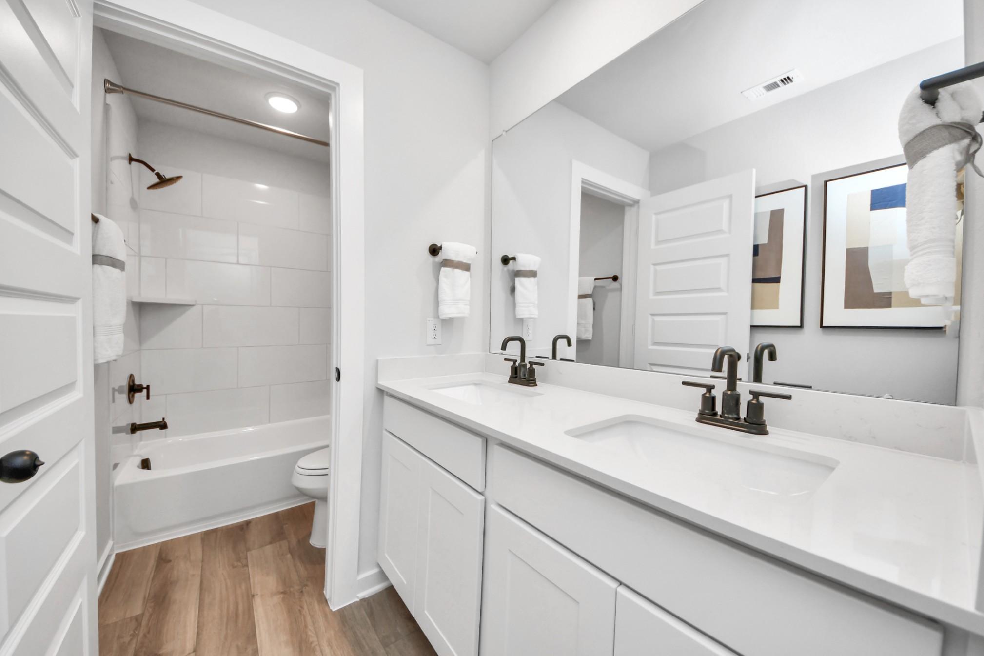 Modern bathroom with double vanity, quartz countertops, and tub-shower combo at Robins Landing in Houston by Davidson Homes.