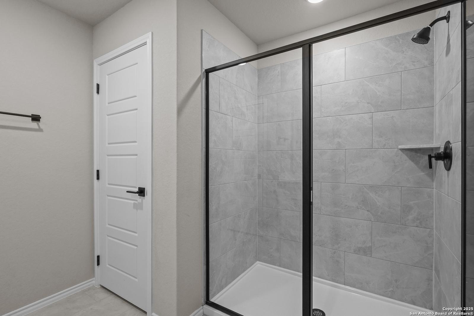 Modern frameless glass walk-in shower with gray subway tiles in master bathroom, Davidson Homes The Murray J, San Antonio
