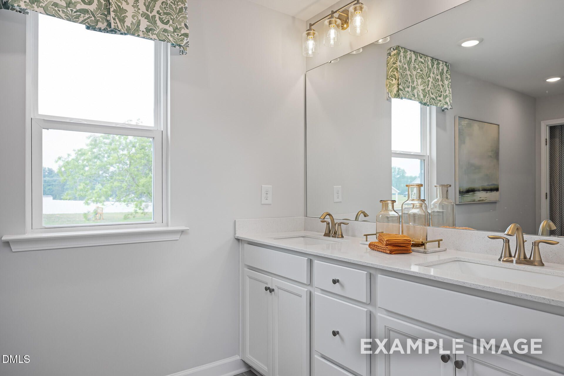 Double vanity bathroom with quartz countertops and gold fixtures in The Adalynn A floor plan, Woodland Crossing, Zebulon.