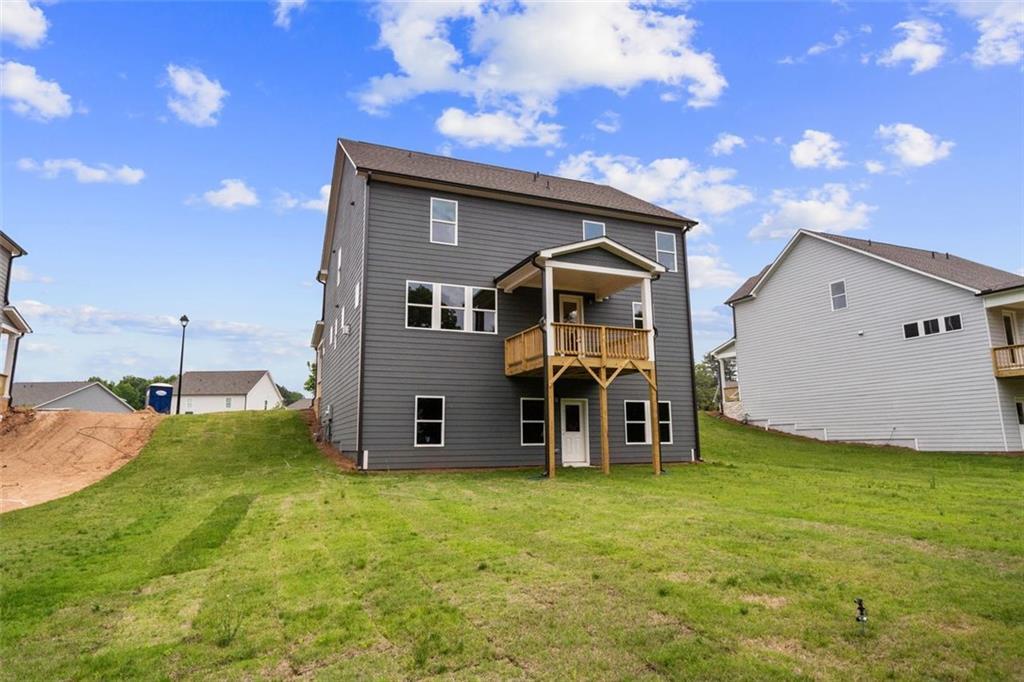 Two-story gray home with covered porch, upper balcony, and green yard in Wehunt Meadows, Hoschton, Georgia by Davidson Homes