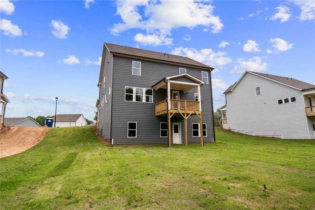 Two-story gray home with covered porch, upper balcony, and green yard in Wehunt Meadows, Hoschton, Georgia by Davidson Homes