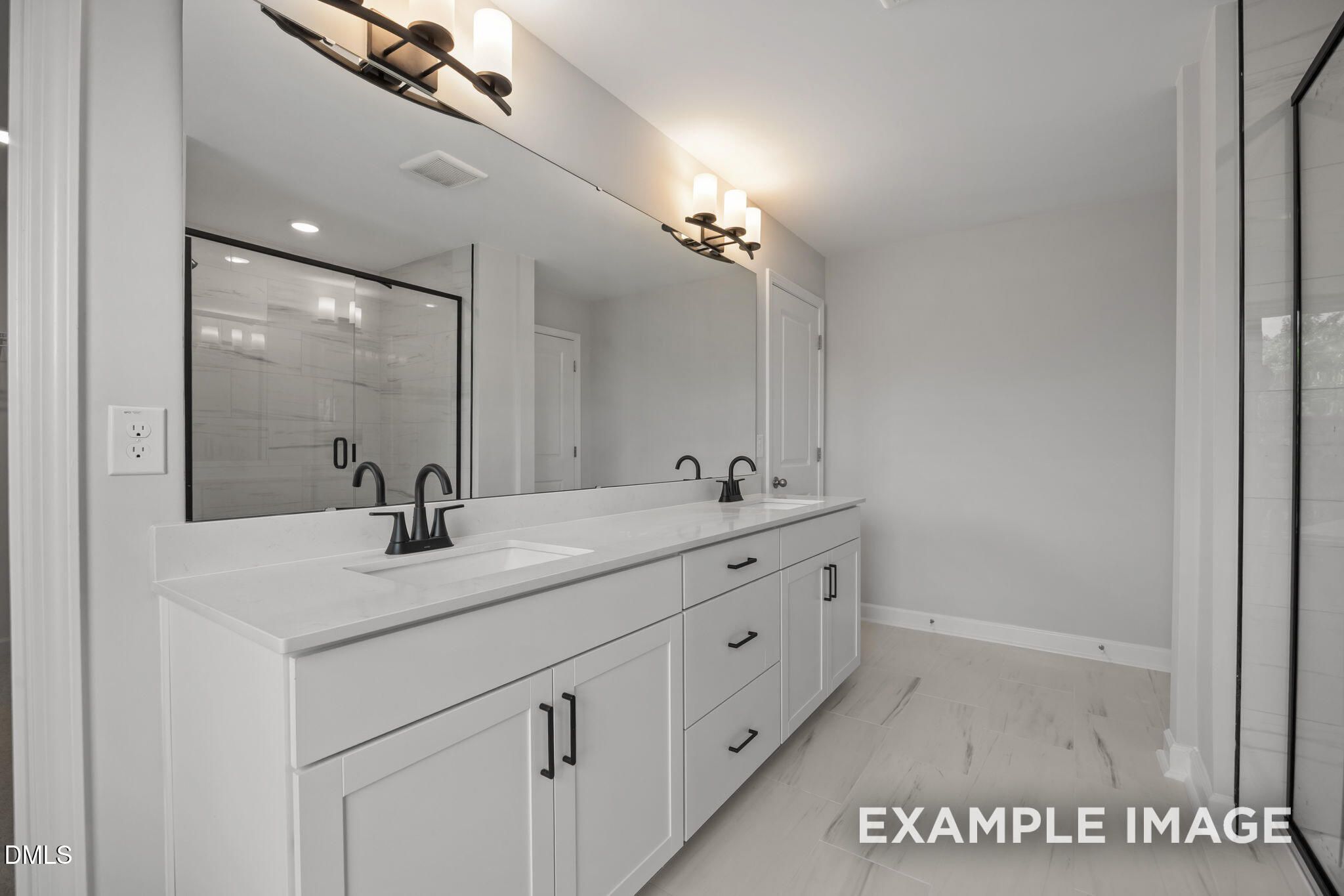 Double vanity bathroom with white cabinetry, black fixtures, and marble tile shower in The Beech floor plan at Wendell Ridge