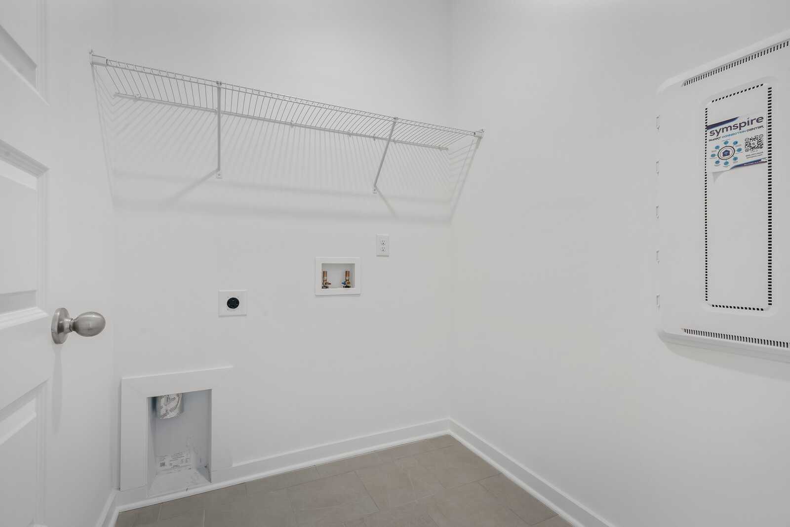 Spacious laundry room in The Asheville plan with wire shelving, washer-dryer hookups, and utility access
