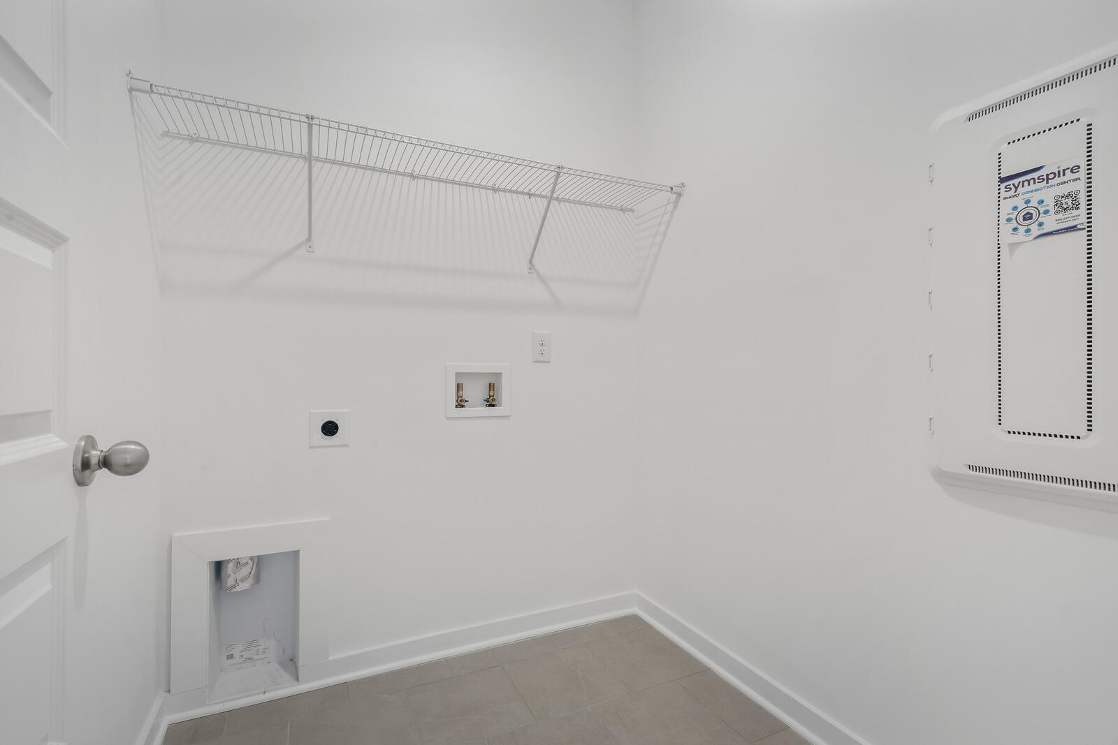 Spacious laundry room in The Asheville by Davidson Homes with wire shelving, utility sink, and washer-dryer hookups
