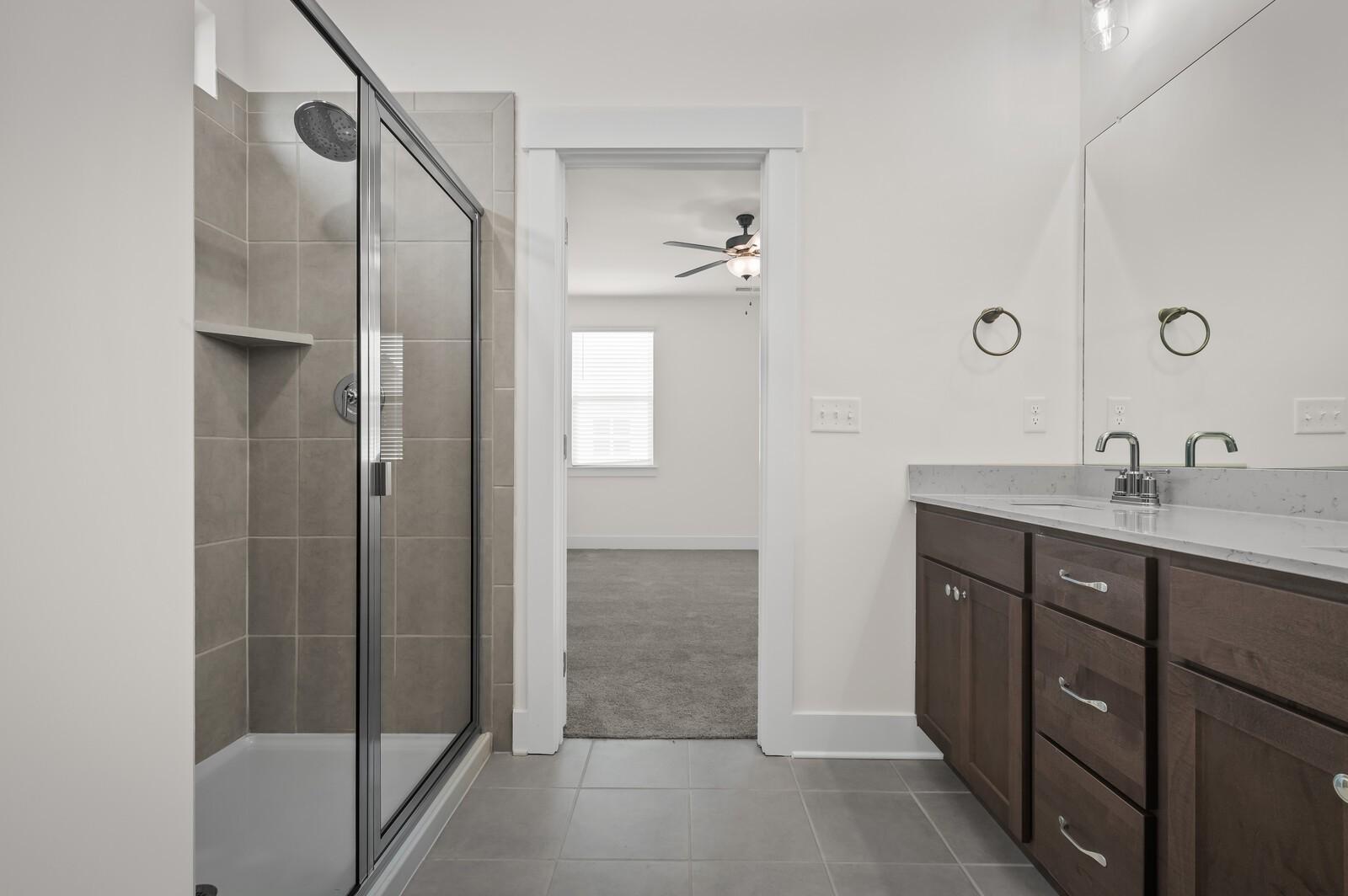 Modern bathroom with tiled walk-in shower and dark wood vanity in The Ash A floor plan at Woods Crossing, Gallatin, TN.