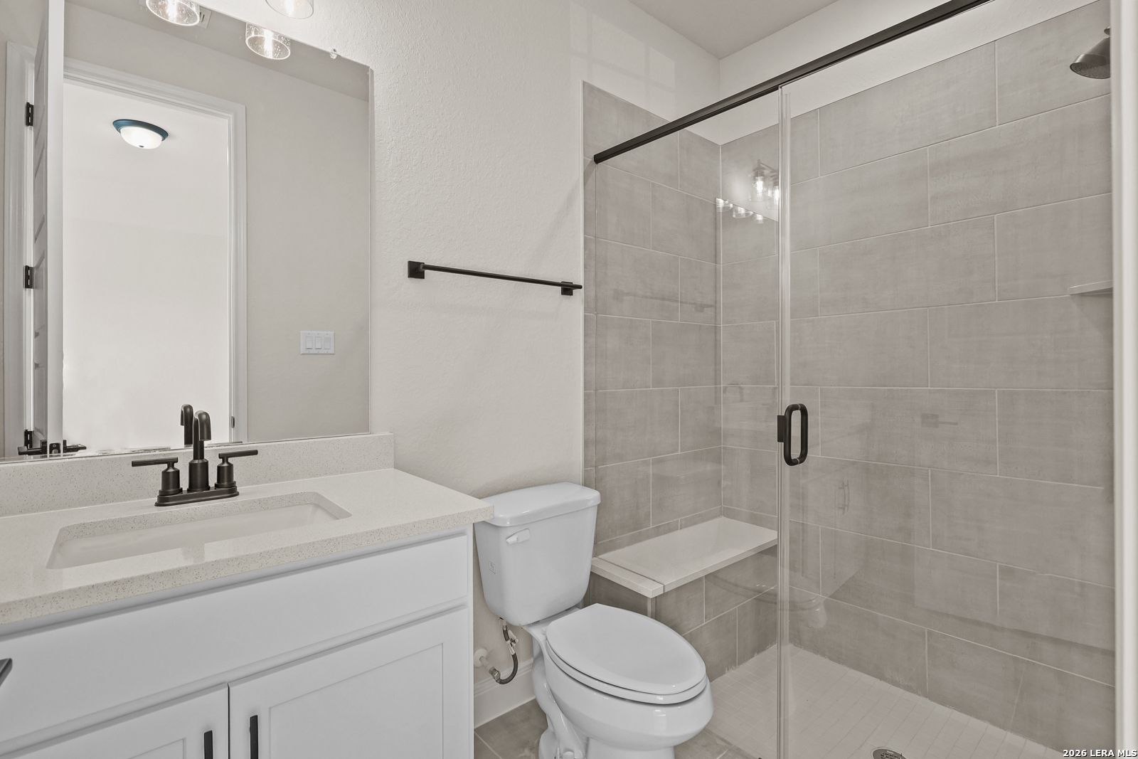 Modern bathroom with glass-enclosed tiled shower and vanity in The Summerlin B floor plan, Potranco Oaks, Castroville, TX.