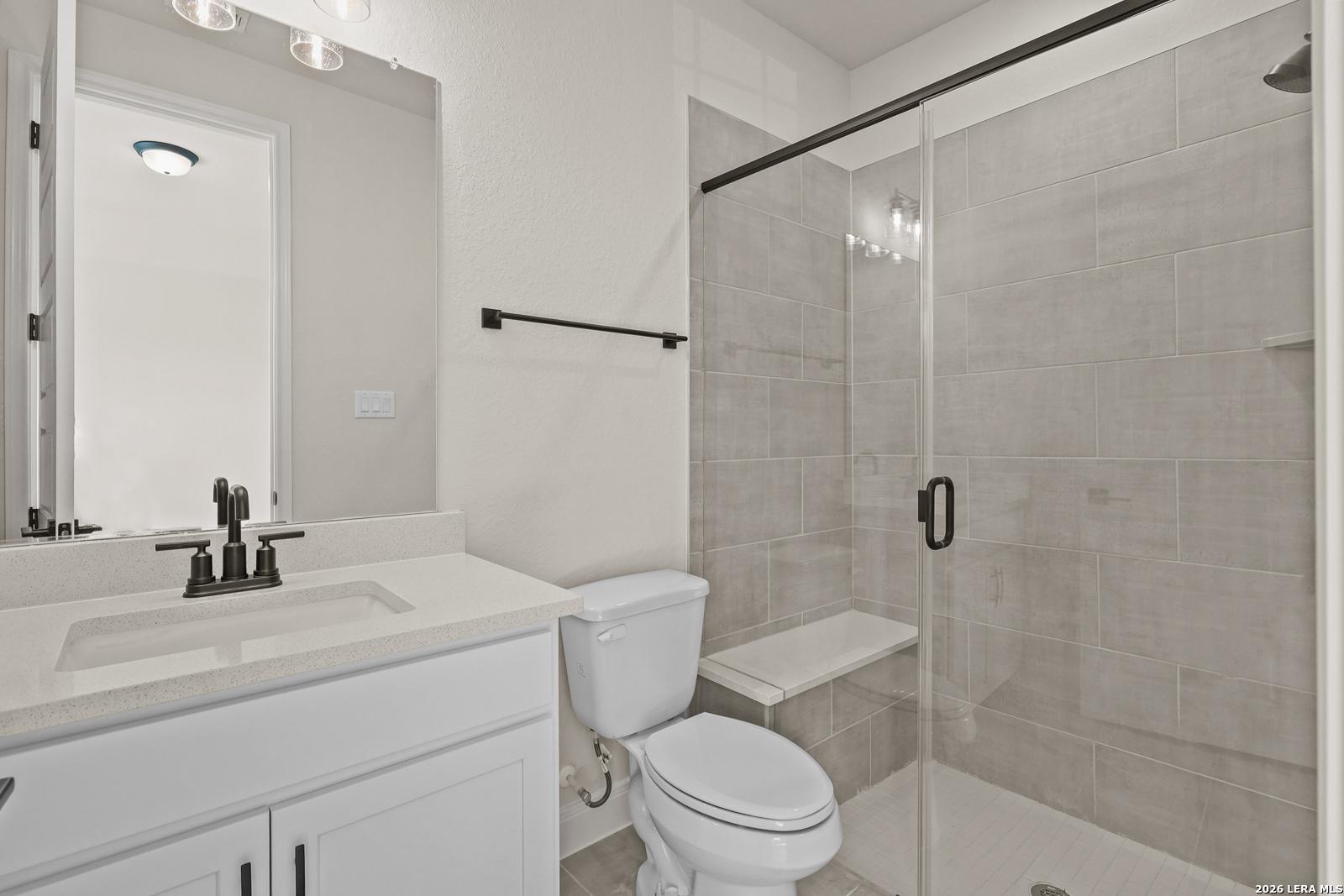 Modern bathroom with glass-enclosed tiled shower and vanity in The Summerlin B floor plan, Potranco Oaks, Castroville, TX.