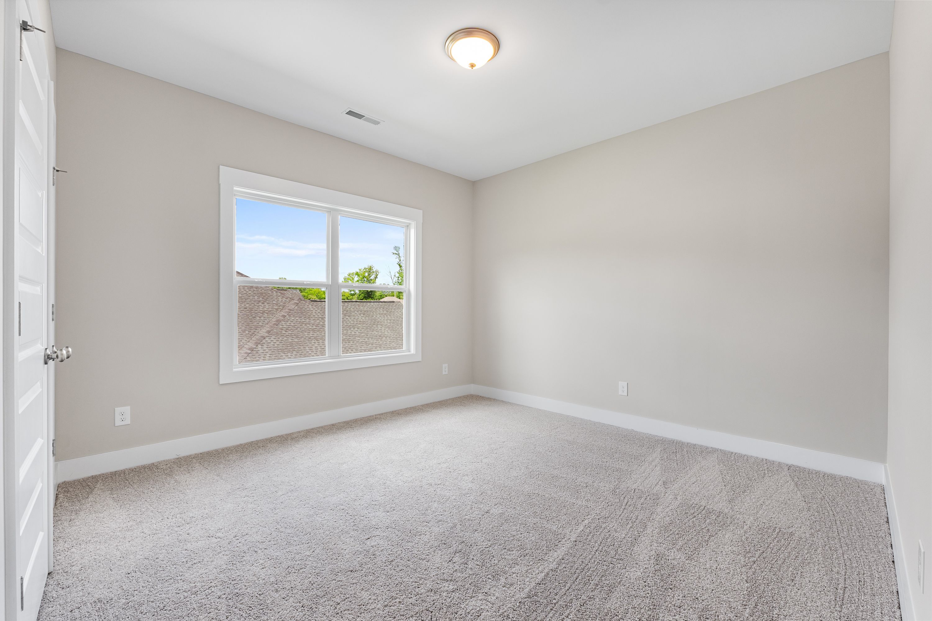 Spacious secondary bedroom in The Oxford A with beige walls, carpeted floor, large window, and ceiling light