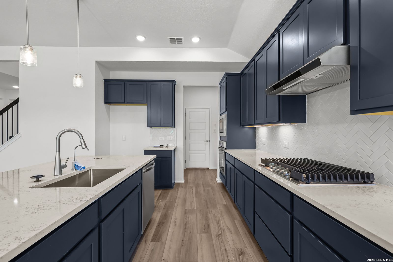 Modern navy kitchen with quartz island, stainless sink, gas range in Davidson Homes Sequoia B, San Antonio