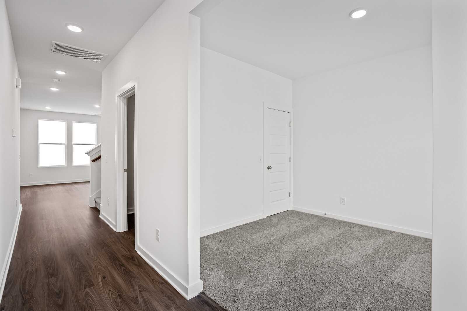Bright hallway with hardwood floors, white walls, recessed lights, and doors in Davidson Homes The Logan C, Sage Farms, White House, TN