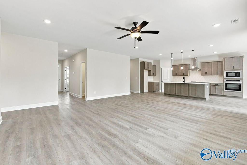 Open-concept living area with luxury vinyl plank flooring and modern kitchen with center island in Davidson Homes Rockford plan, Hartselle AL
