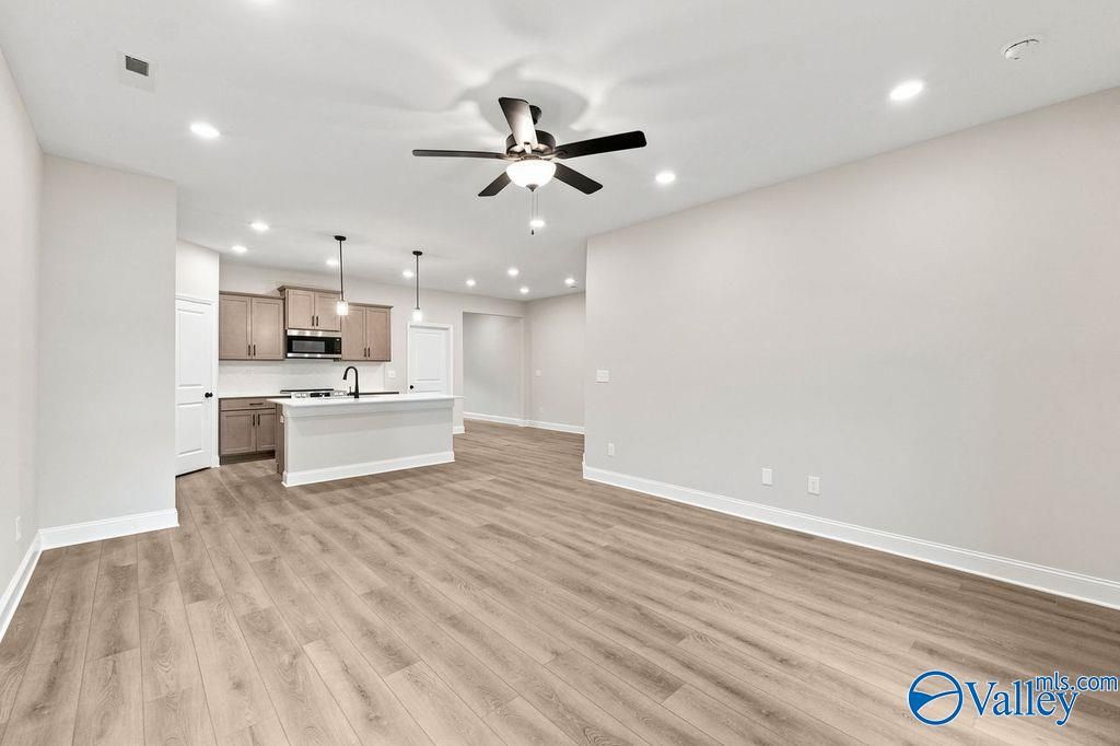 Open-concept living room and kitchen with wood floors in The Camilla C floor plan at The Retreat at Cain Park, Hartselle.