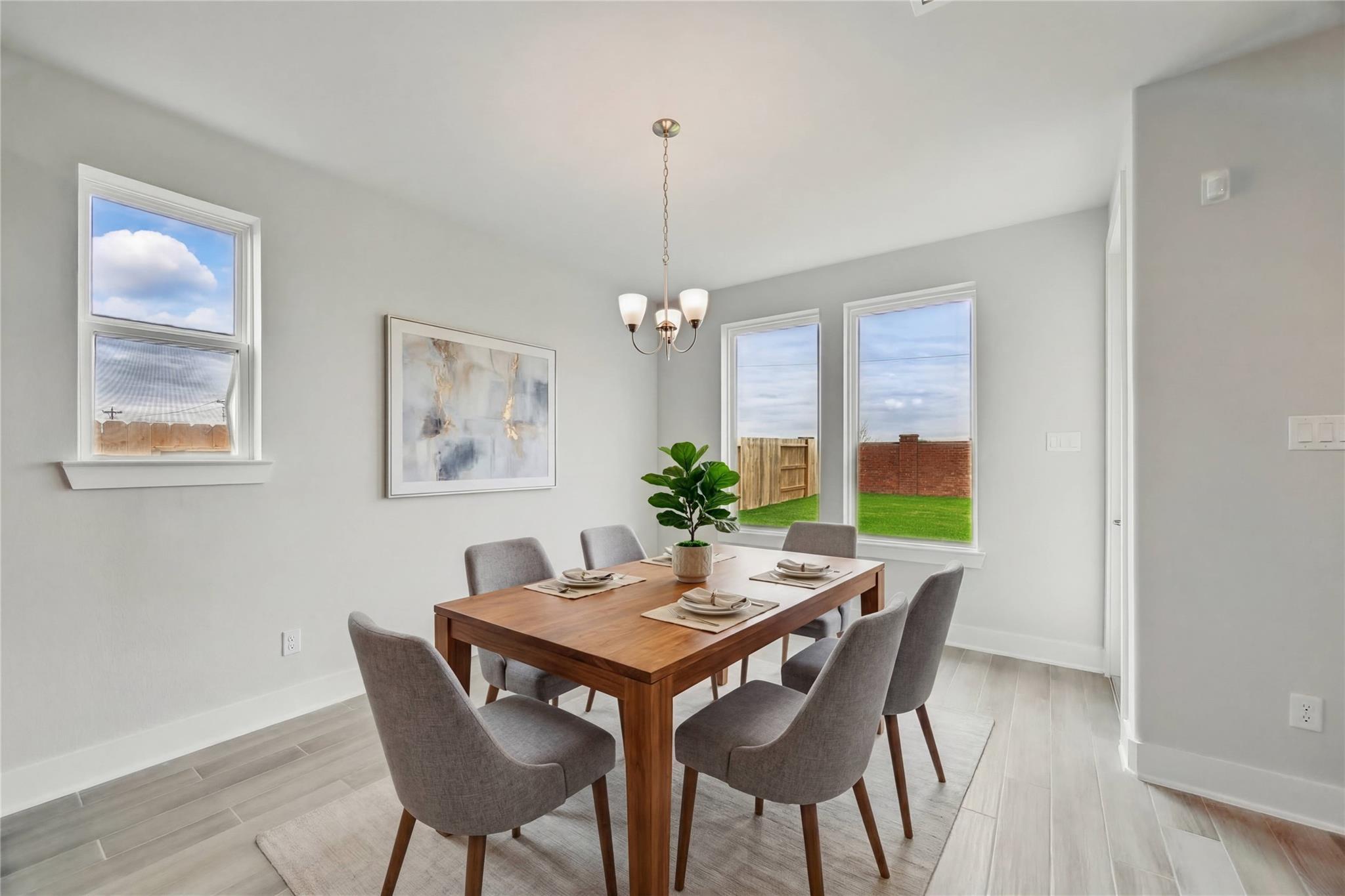 Modern dining room with wooden table, gray chairs, chandelier, and backyard view in Davidson Homes The Philip A, Lago Mar, Texas
