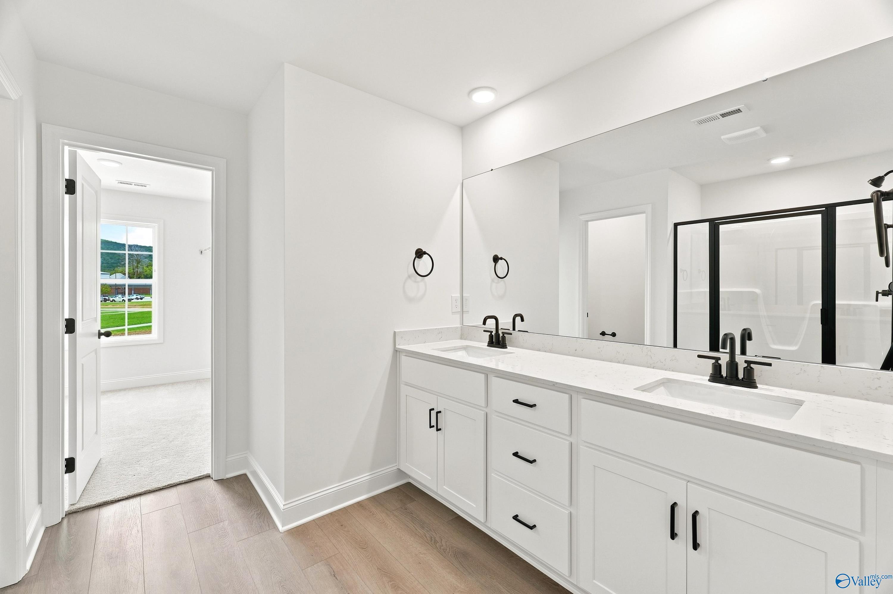 Modern primary bathroom with double vanity, white cabinets, and walk-in shower in The Shelby B home, Jaguar Hills, Huntsville.
