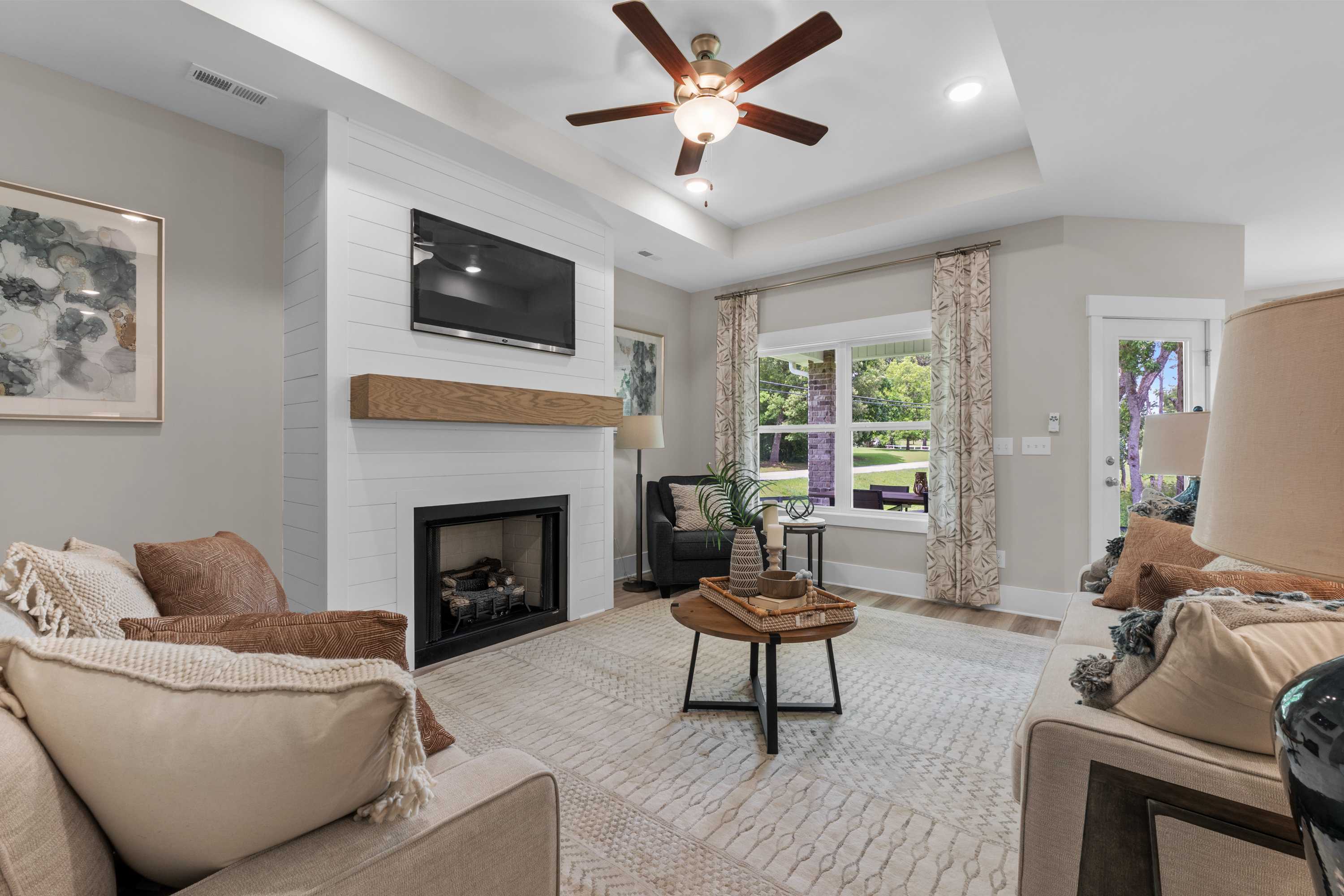 Cozy living room at The Highlands in Arab Alabama with shiplap fireplace, ceiling fan, large windows and plush seating