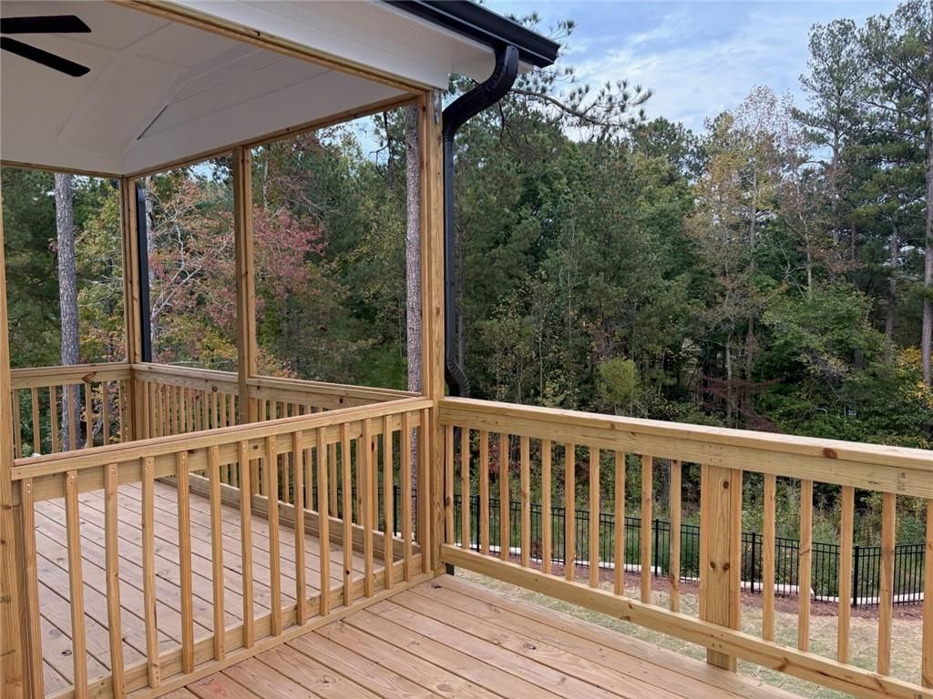 Screened porch with wooden deck, railings, and ceiling fan overlooking wooded backyard in Davidson Homes The Hickory A, Riverwood, Dallas, Georgia