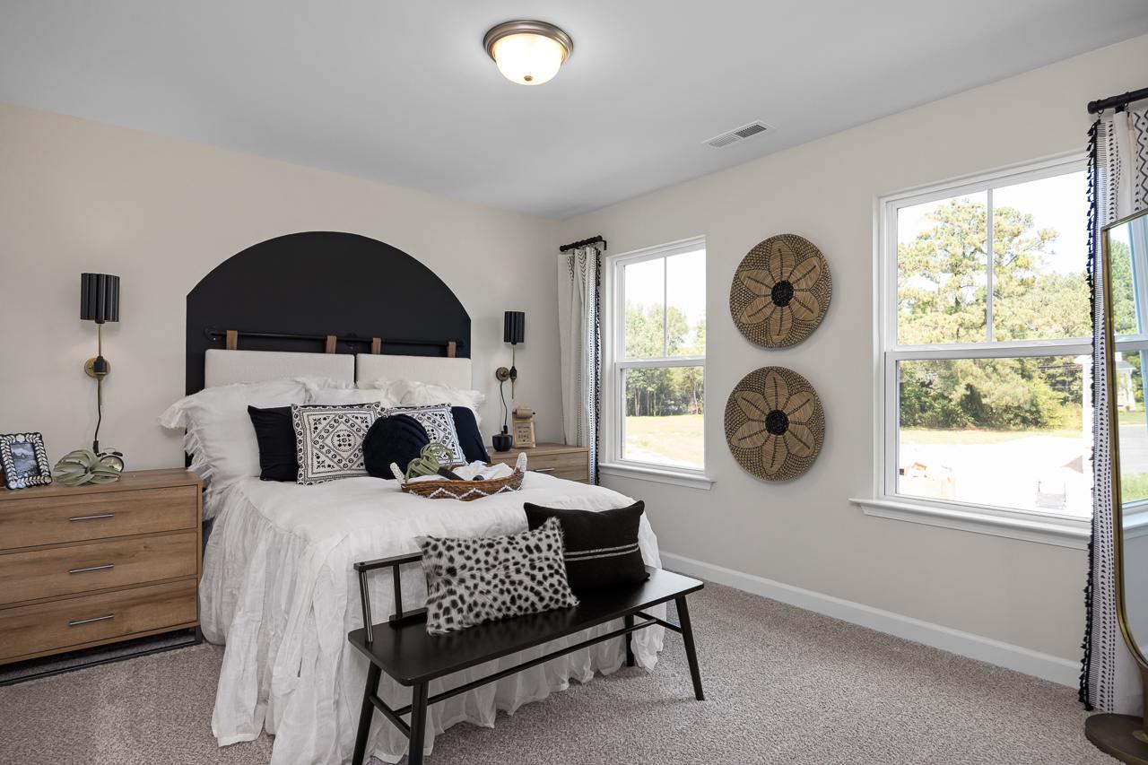 Cozy master bedroom at Wellers Knoll in Lillington NC by Davidson Homes with black headboard, woven wall art and natural light